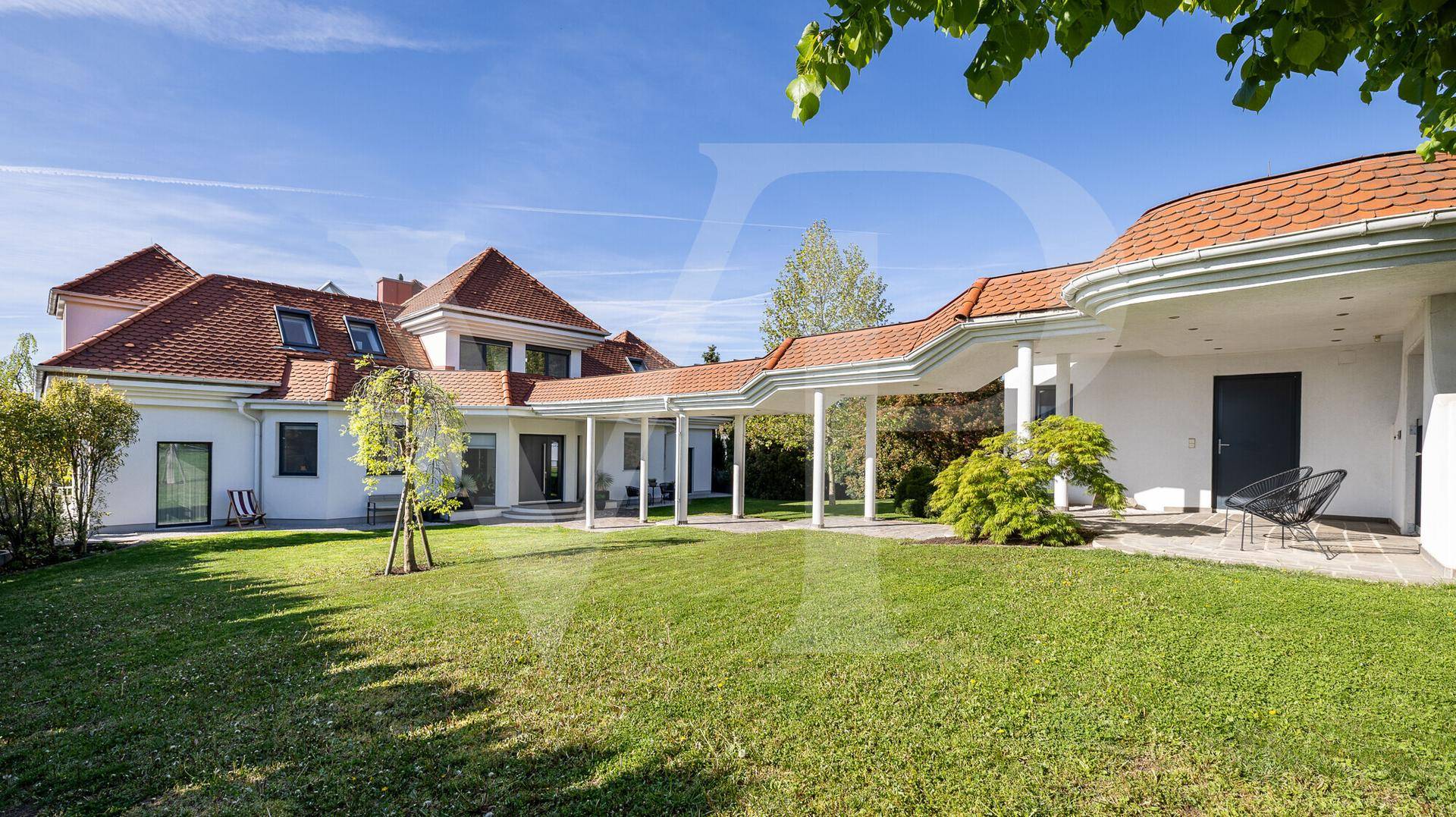 Weitläufiger Garten mit großer Rasenfläche und der eleganten Architektur der Villa.