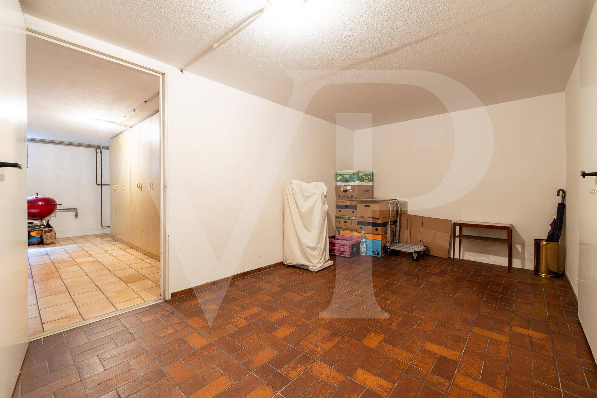 Praktischer Kellerraum mit Fliesenboden und viel Platz für Lagerung und Abstellmöglichkeiten.