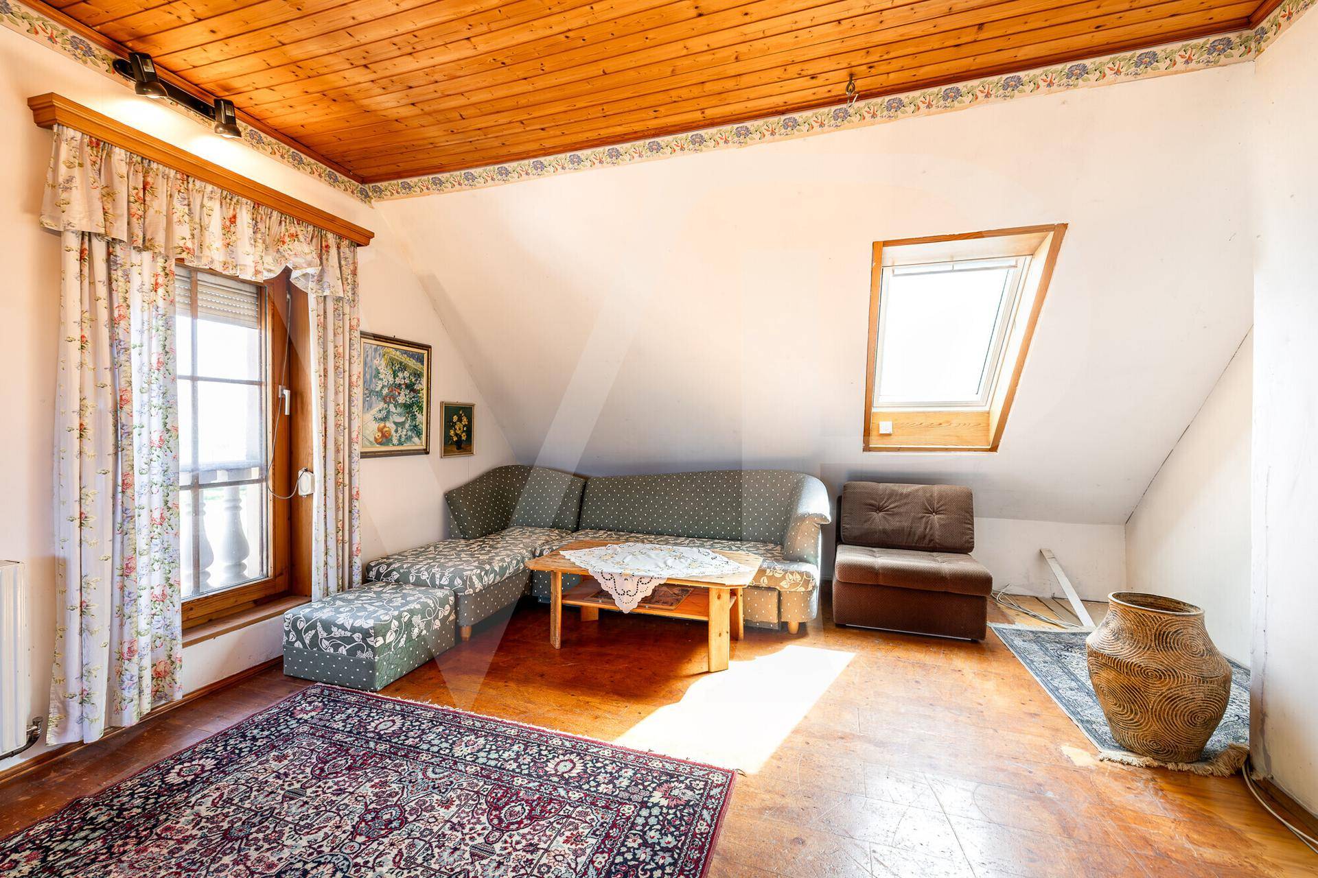 Helles Schlafzimmer im Dachgeschoss mit Holzboden, Dachfenster und gemütlicher Sitzecke.