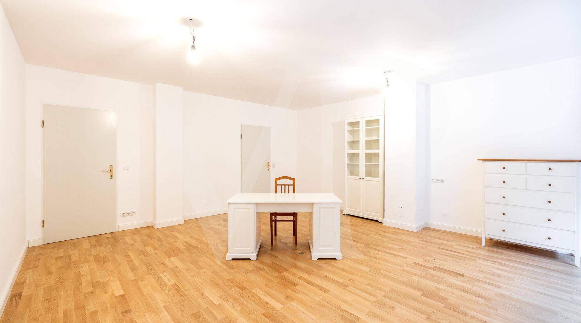 Helles Zimmer mit Parkettboden und einfacher Einrichtung, ideal als Büro oder Schlafzimmer.