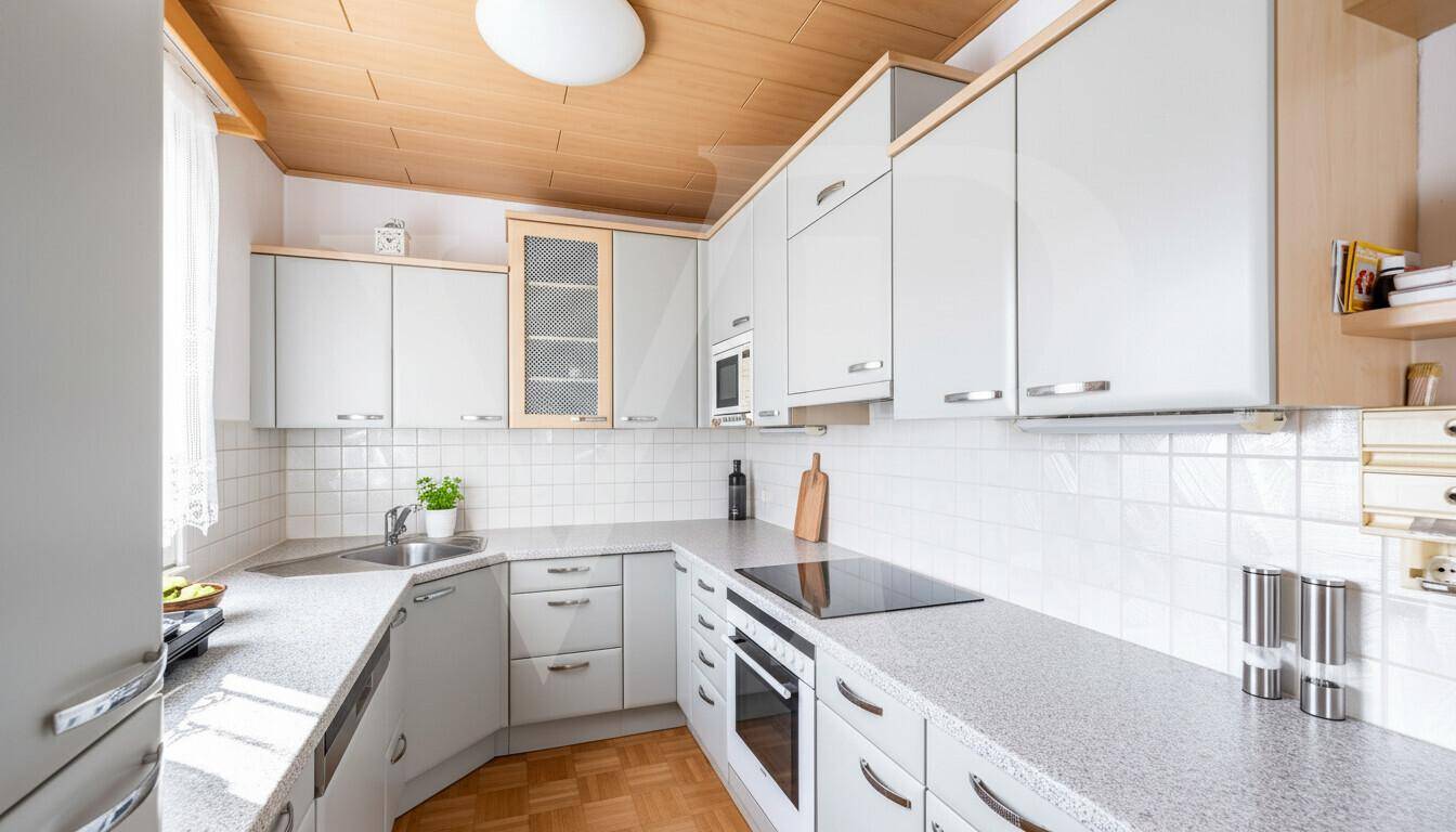Funktionale Küche mit hellgrauen Schränken, Fliesenrückwand und Parkettboden.