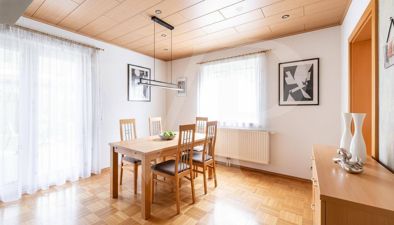 Heller Essbereich mit Holztisch, Parkettboden und großem Fenster.