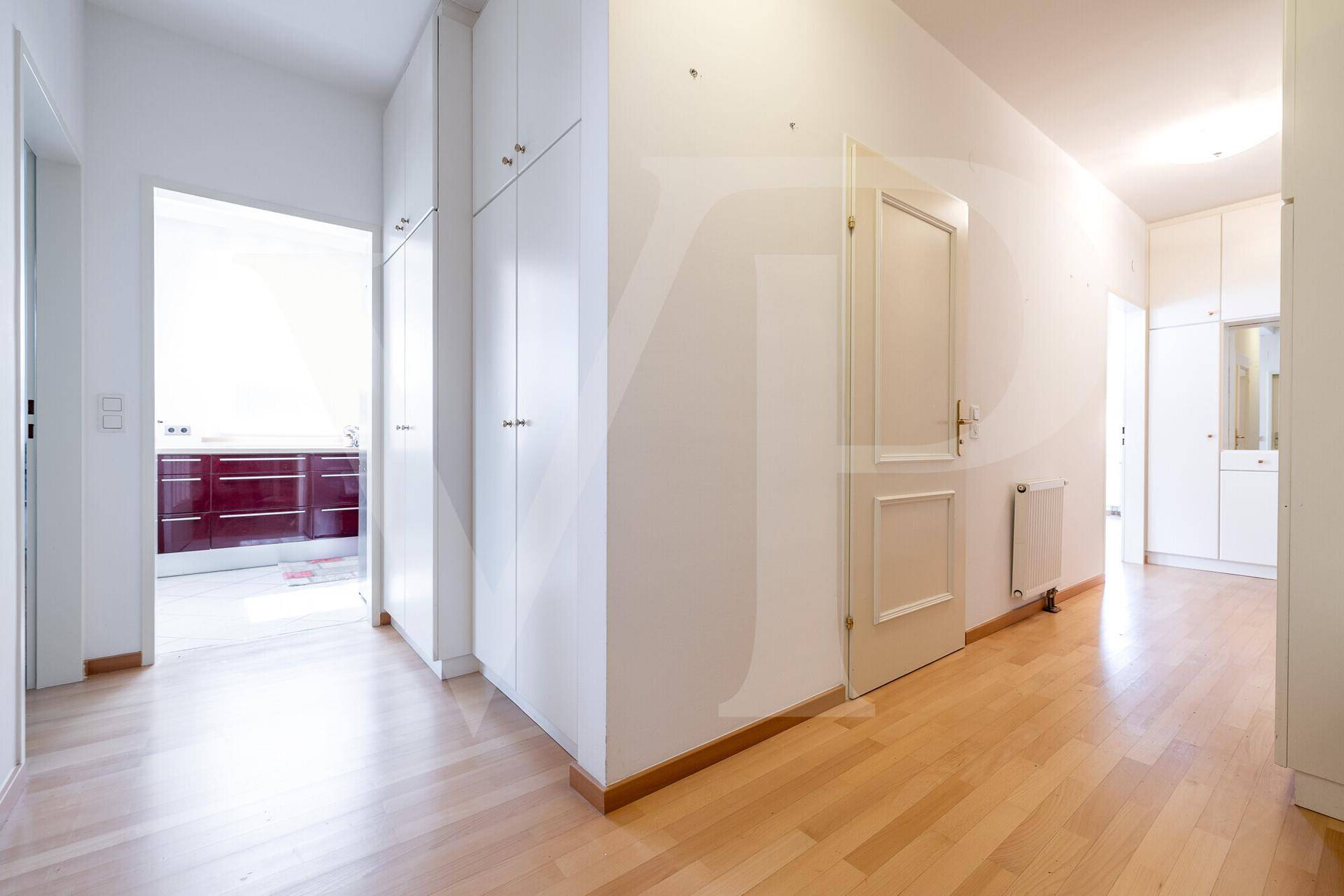 Heller Flur mit Holzfußboden und praktischen Einbauschränken, der zur Küche führt.