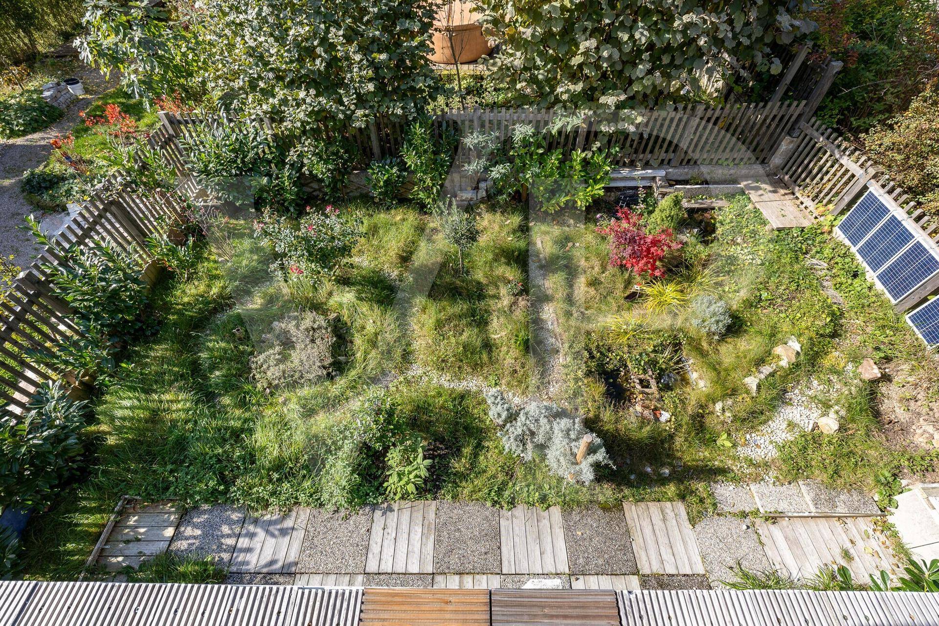 Helles Schlafzimmer mit Holzboden, schrägen Wänden und Zugang zu einem kleinen Balkon.