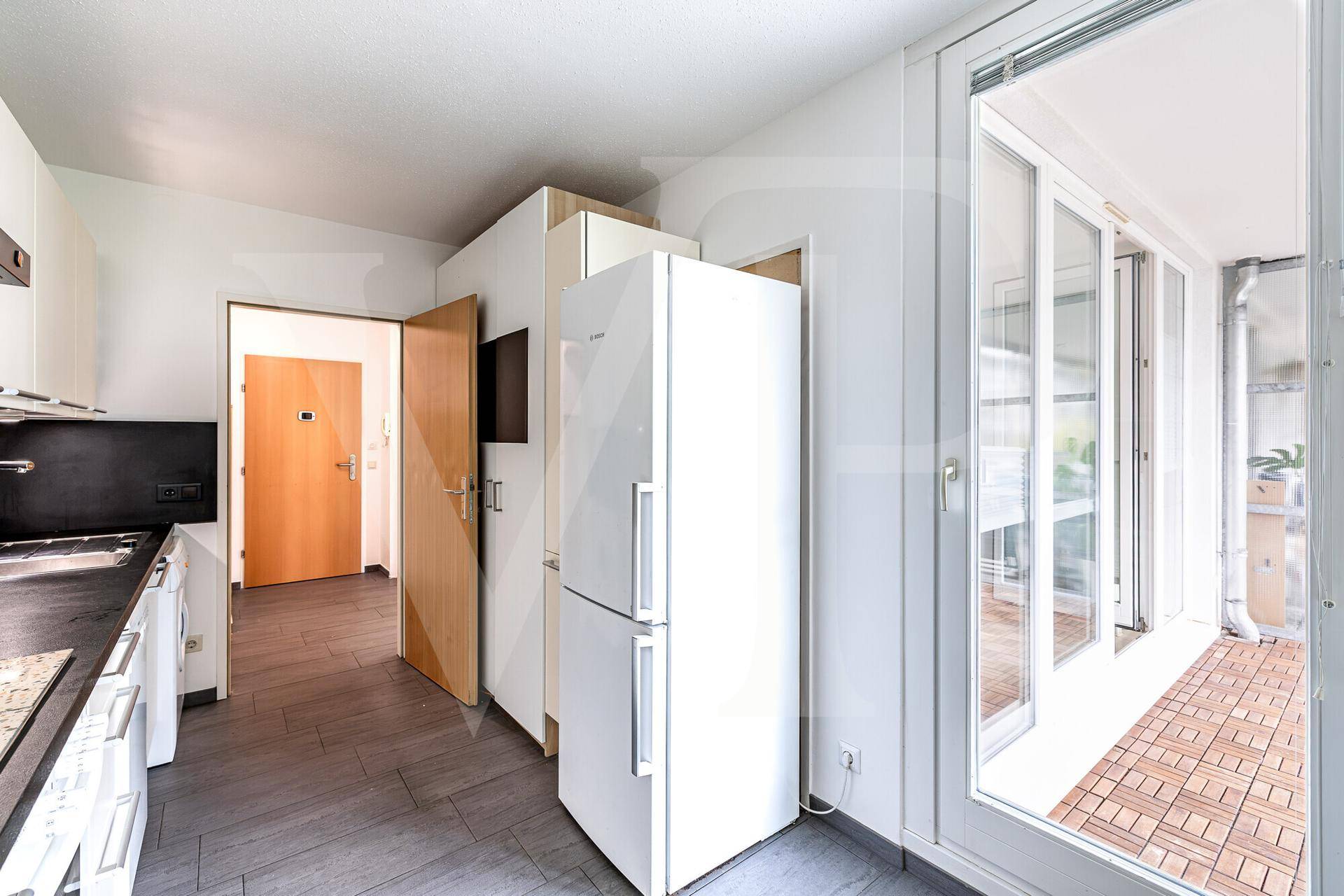 Helle Küche mit Einbaugeräten und direktem Zugang zur Loggia, inklusive Kühlschrank.