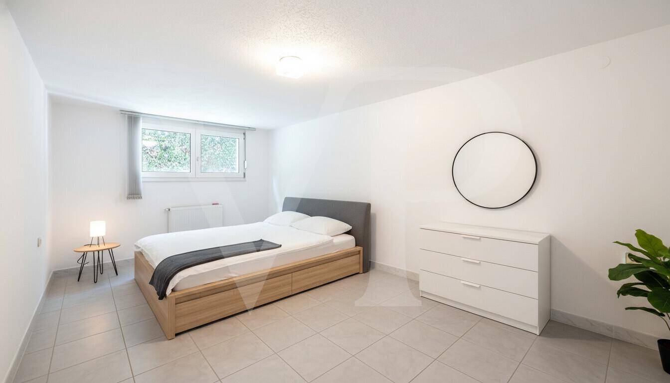 Helles Schlafzimmer mit Doppelbett, Kommode und Fliesenboden.