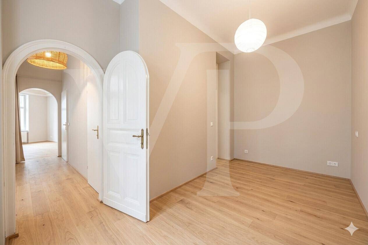 Heller Flur mit eleganten Rundbögen und einer stilvollen weißen Tür, die zu weiteren Räumen führt.