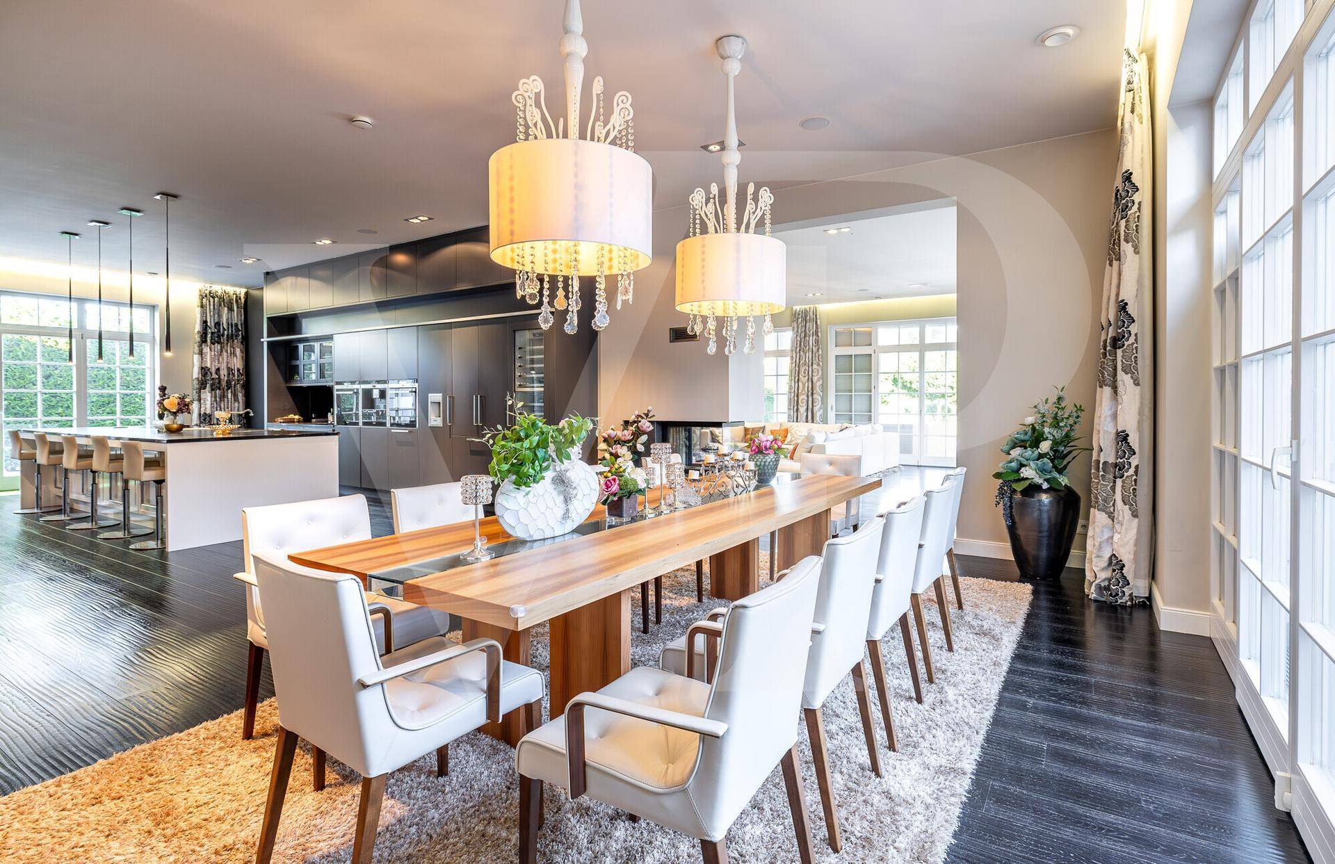 Eleganter Essbereich mit langem Holztisch, Kronleuchtern und offener Verbindung zur Küche.