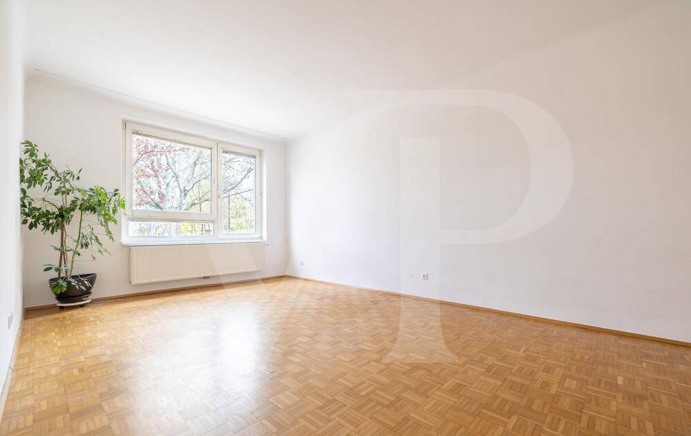 Geräumiges, helles Zimmer mit Parkettboden und großem Fenster.