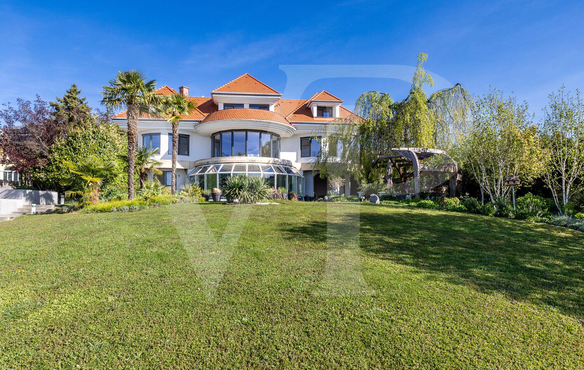 Beeindruckende Villa mit weitläufigem Rasen und tropischer Bepflanzung unter blauem Himmel.