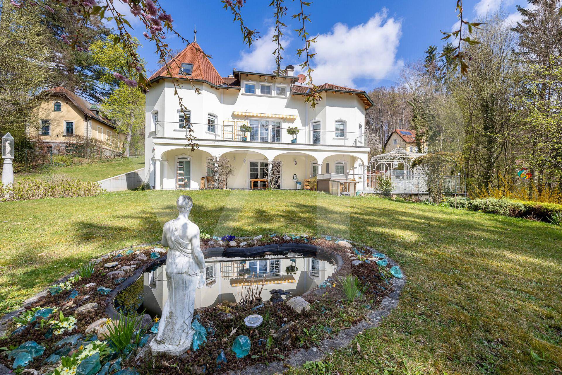 Eindrucksvolle Villa mit weitläufigem Garten, dekorativem Teich und üppiger Vegetation.