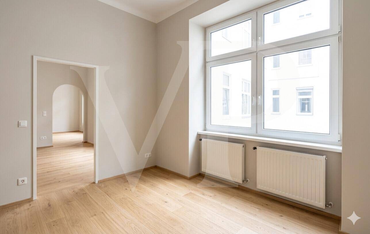 Geräumiges Zimmer mit großen Fenstern, hellem Parkettboden und Heizkörpern unter der Fensterbank.