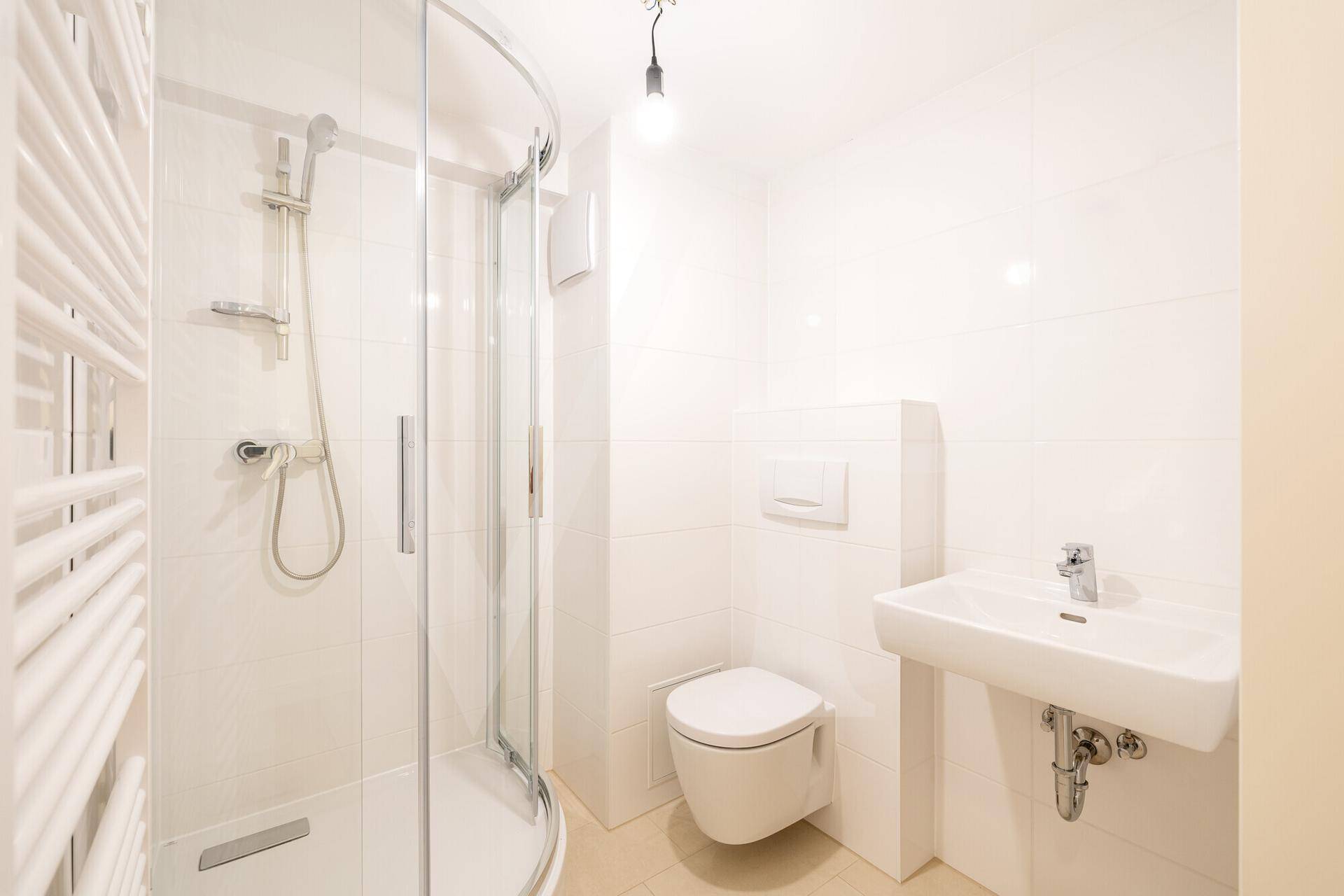 Modernes Badezimmer mit Duschkabine, wandhängendem WC, Waschbecken und Handtuchheizkörper.