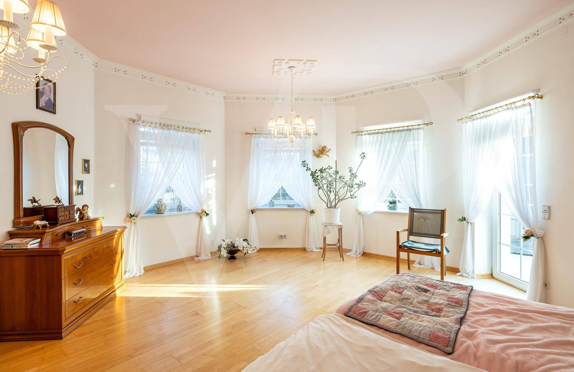 Geräumiges Schlafzimmer mit Holzboden, Kommode und viel Tageslicht durch die Fenster.