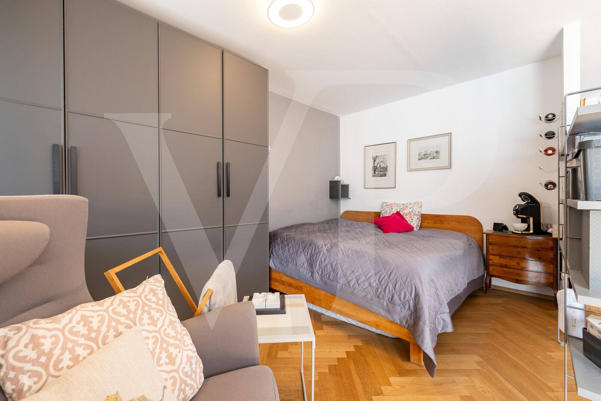 Schlafzimmer mit Holzbett, Einbauschränken und Fischgrätparkett, hell und funktional eingerichtet.
