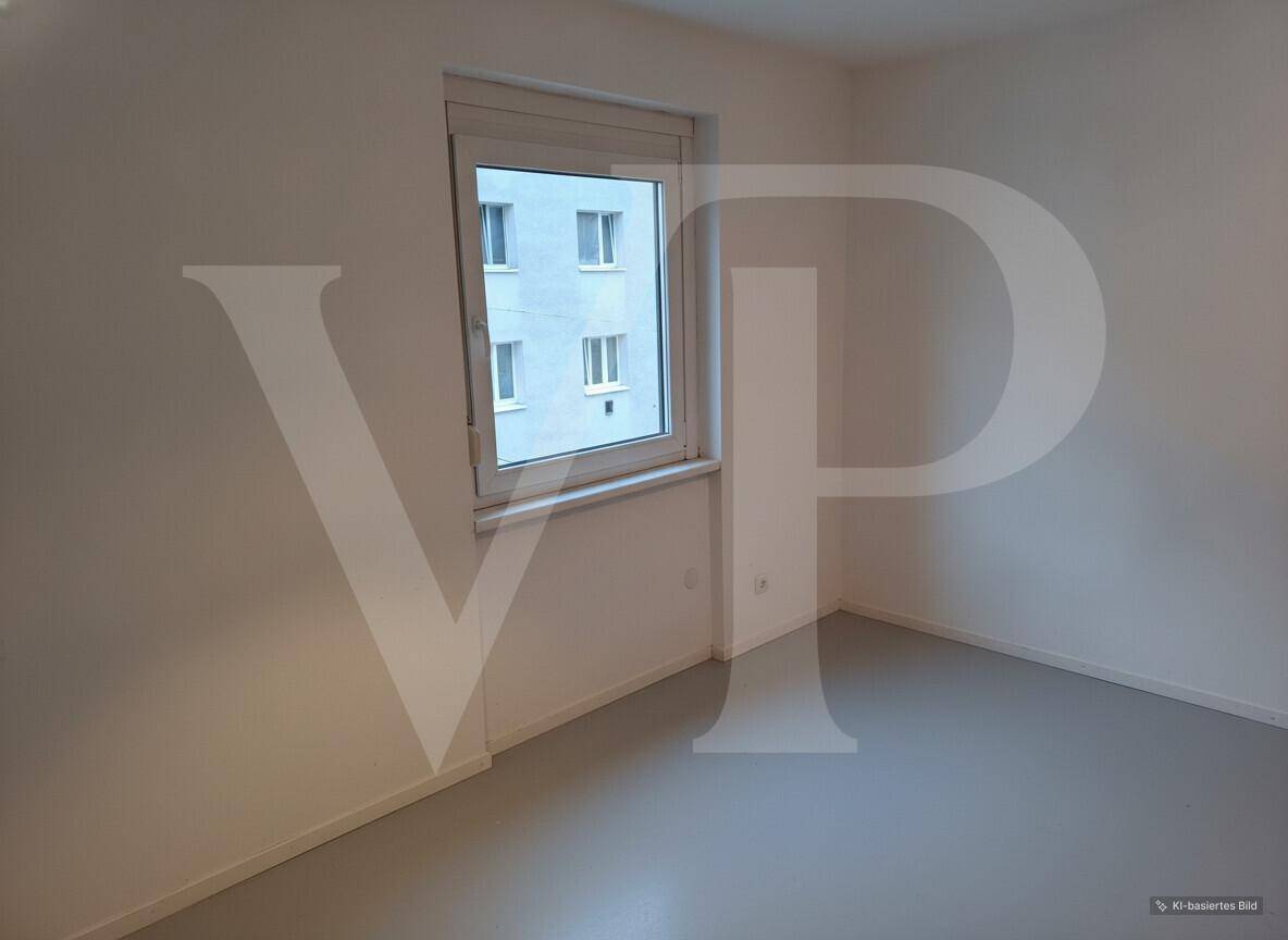 Kleines, helles Zimmer mit einem Fenster und dunklem Laminatboden.