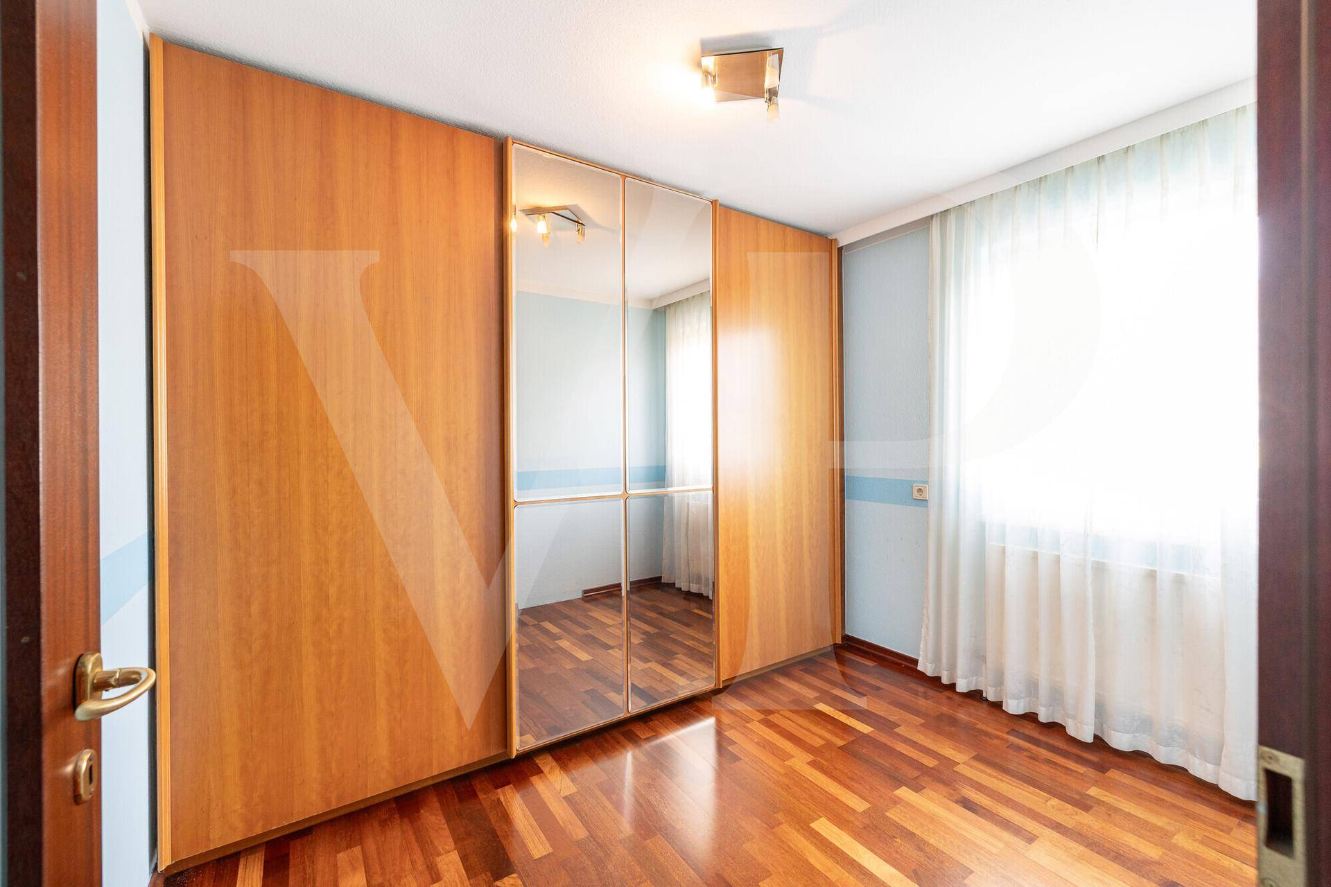 Schlafzimmer mit Holzboden und großen Einbauschränken, die viel Stauraum bieten.