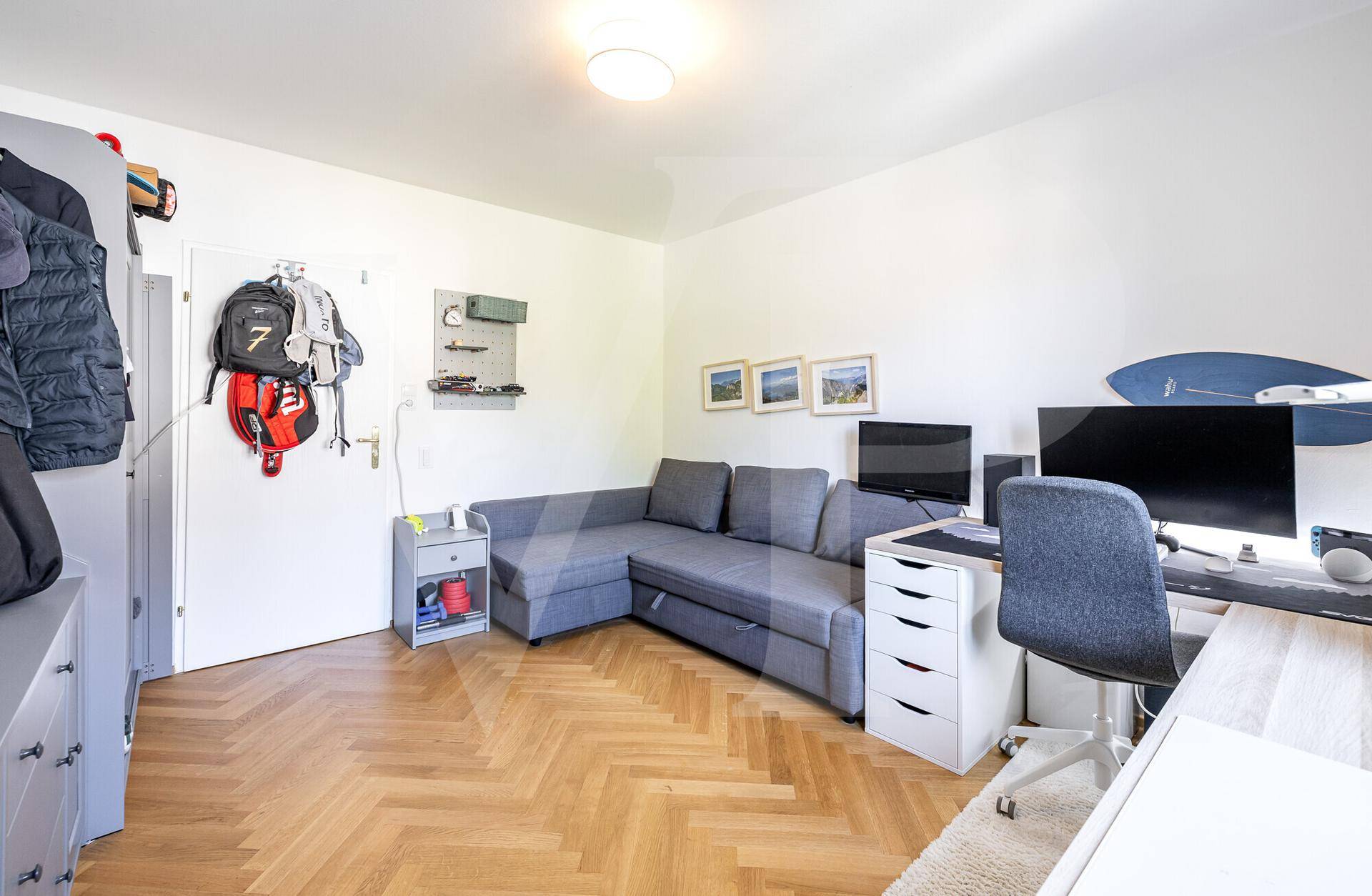 Arbeitszimmer mit Sofa, Schreibtisch und Stauraum, funktional und hell gestaltet.
