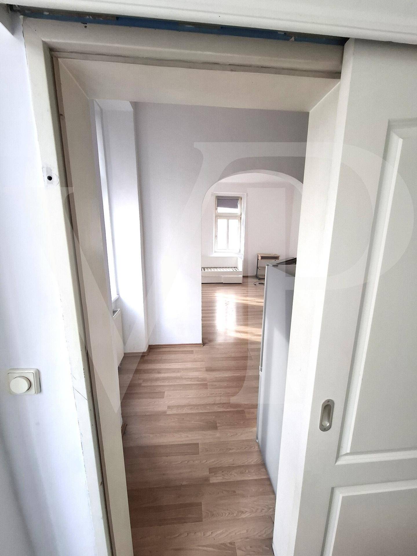 Funktionale Küche mit hellen Schränken, Holzarbeitsplatte und Laminatboden.