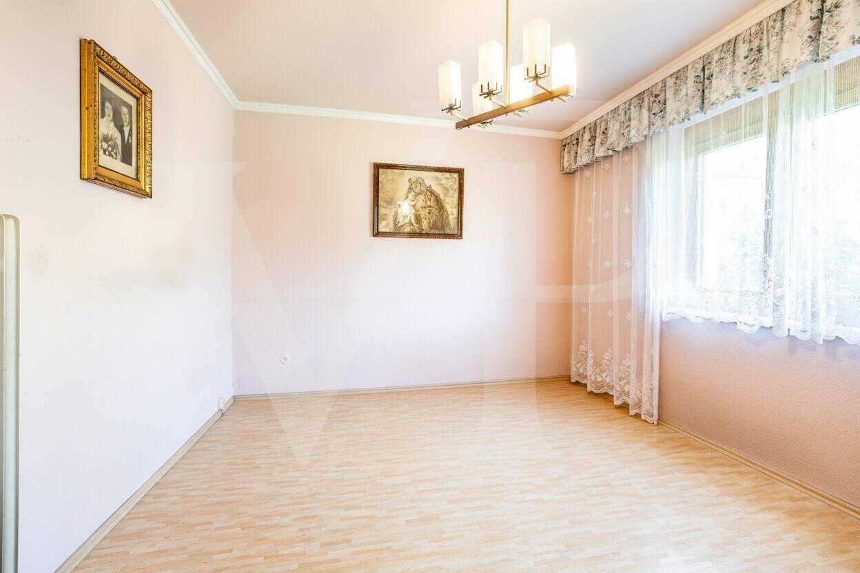 Helles Schlafzimmer mit Laminatboden, rosa Wänden und großem Fenster.