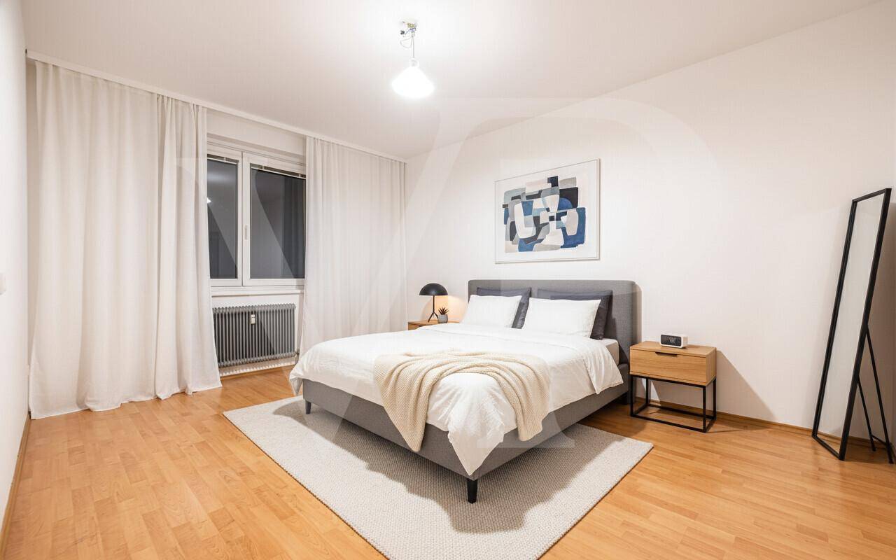 Stilvolles Schlafzimmer mit Holzbett, grünen Wänden und Parkettboden, einladend und wohnlich gestaltet.