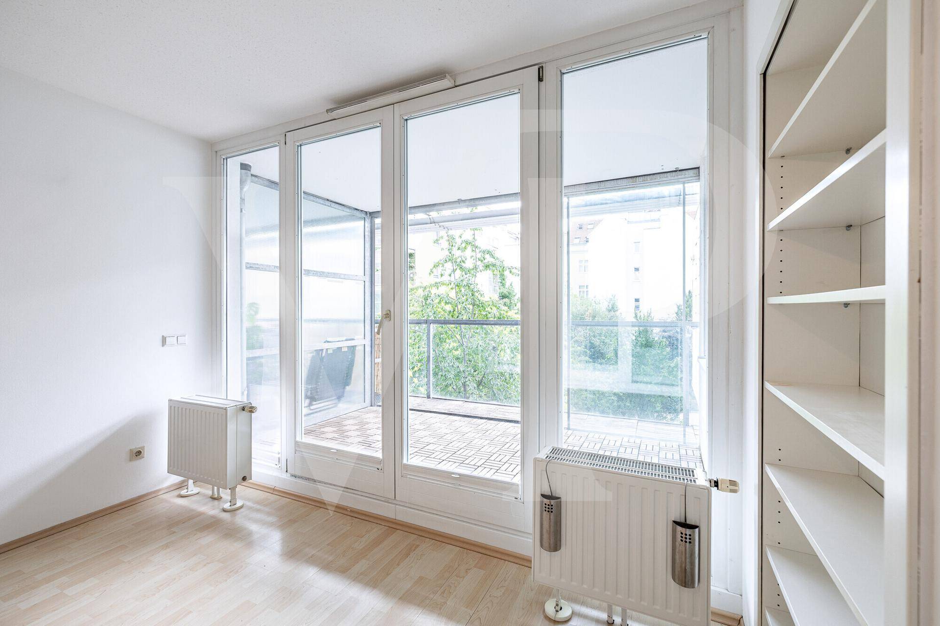 Helles Wohnzimmer mit großen Fenstern und Blick ins Grüne, ausgestattet mit Heizkörpern.