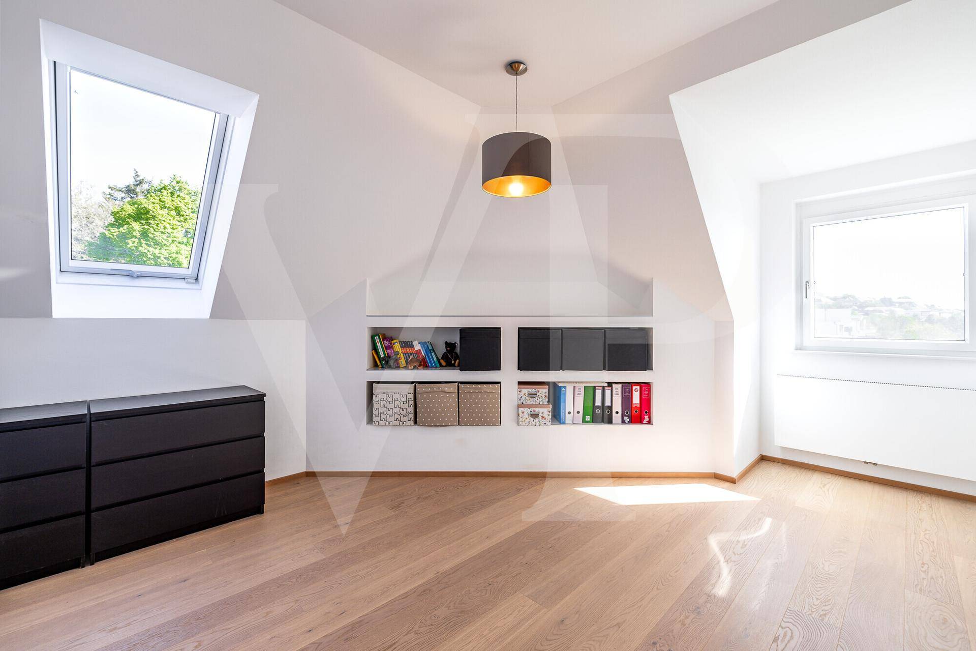 Geräumiger Dachraum mit Holzboden, Dachfenstern und integrierten Ablagemöglichkeiten.