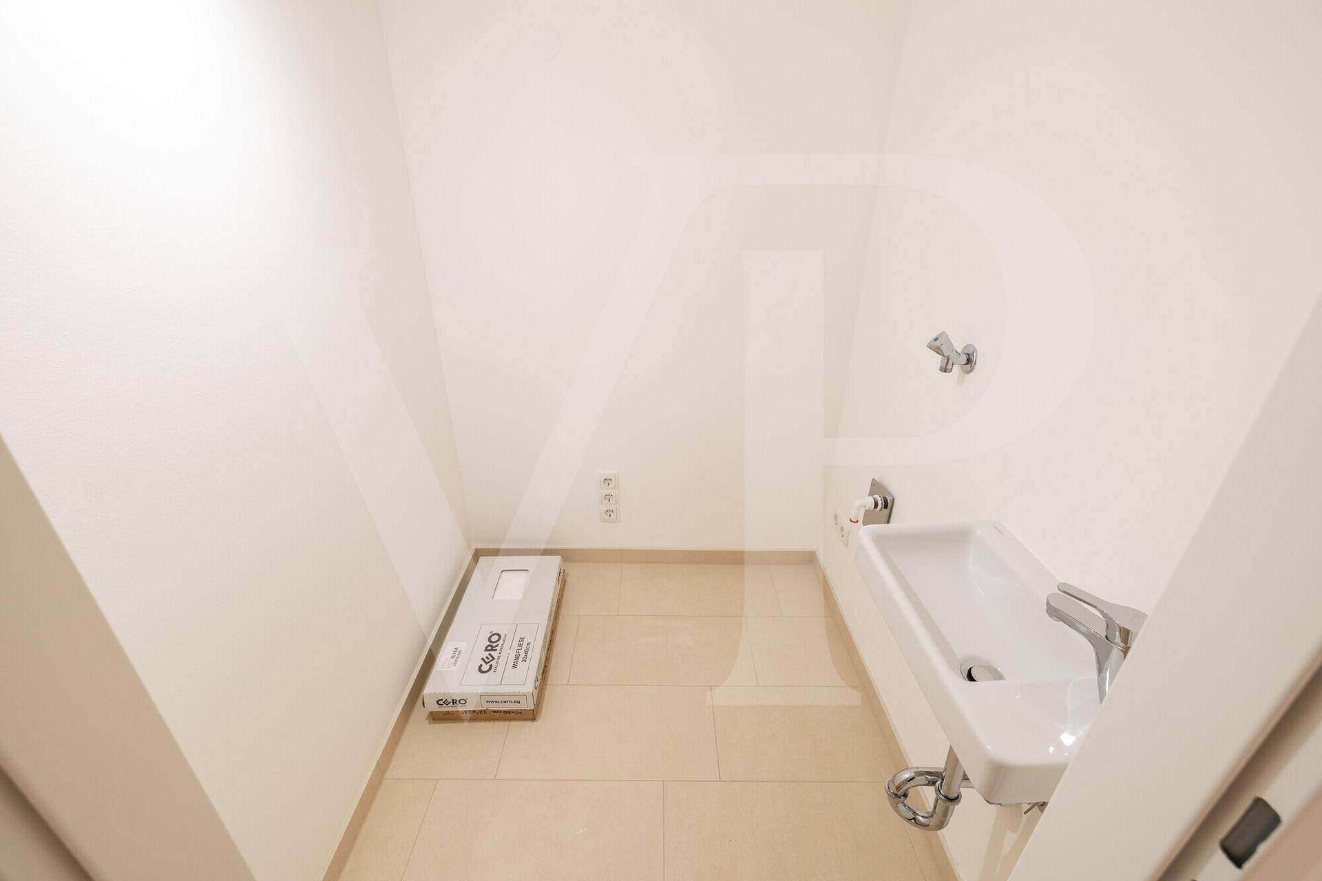 Kleiner Raum mit Waschbecken und Fliesenboden, ideal als Gäste-WC oder Abstellraum.