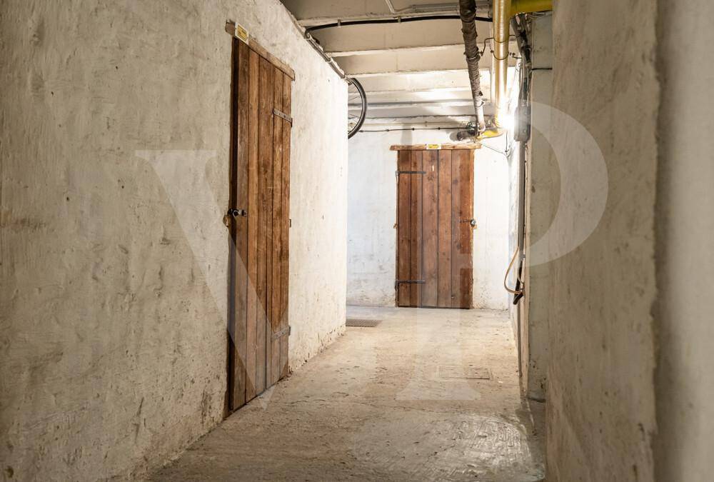 Kellerflur mit robusten Holztüren zu den einzelnen Abteilen.