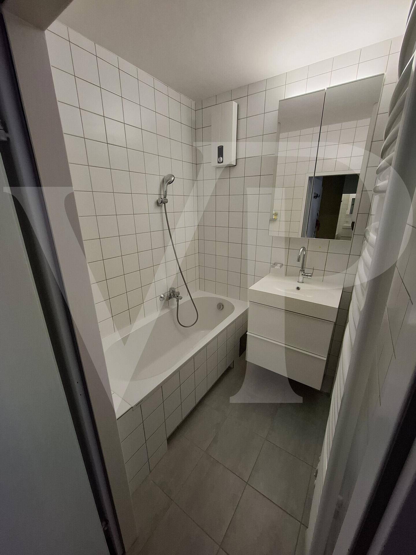 Separates WC mit Toilette, Waschmaschine und weißen Wandfliesen.