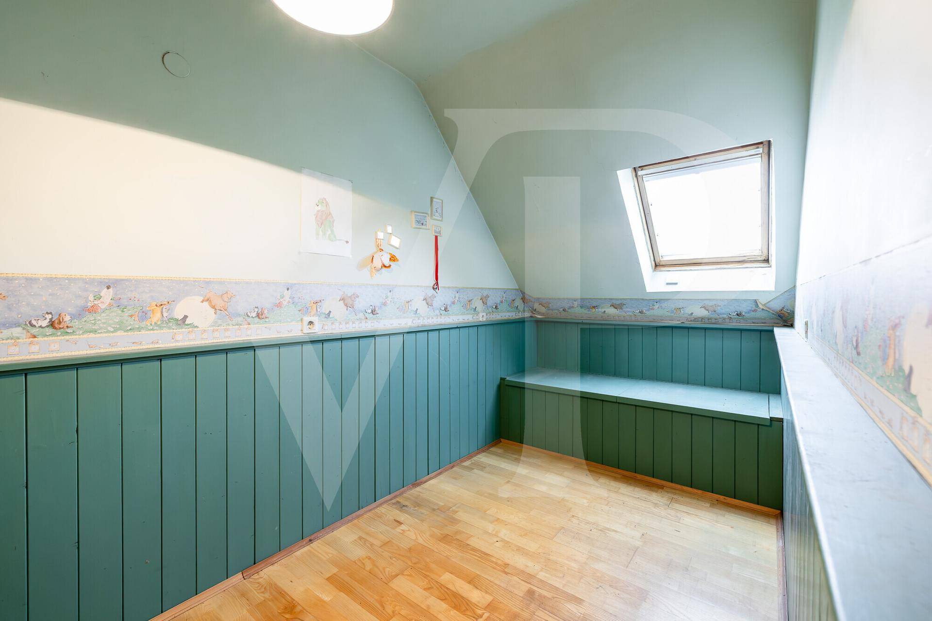 Kinderzimmer im Dachgeschoss mit Holzboden, Dachschräge und einer eingebauten Sitzbank.