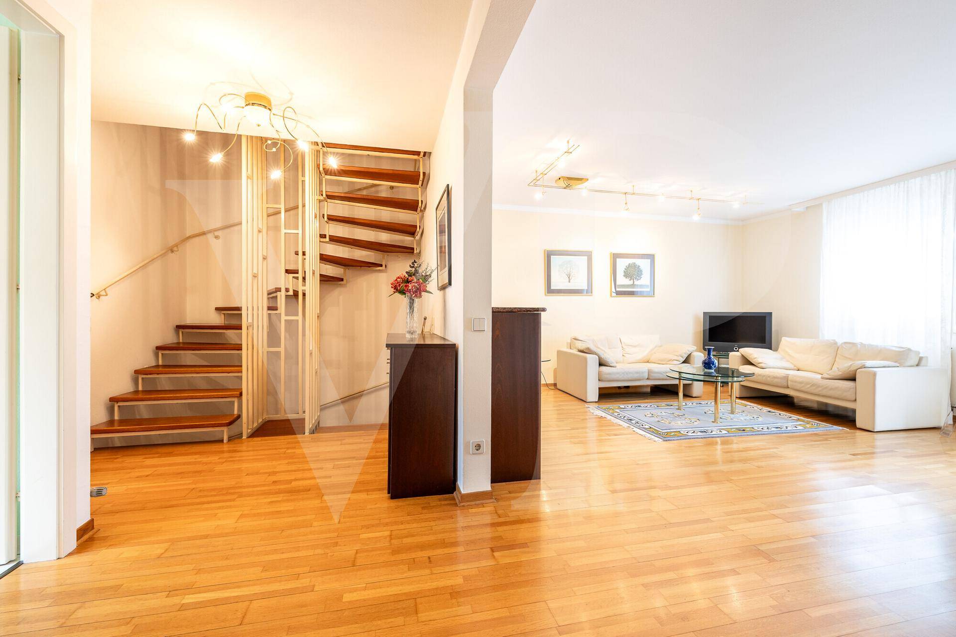 Offener Wohnbereich mit Holztreppe, Parkettboden und Zugang zum Ess- und Wohnzimmer.
