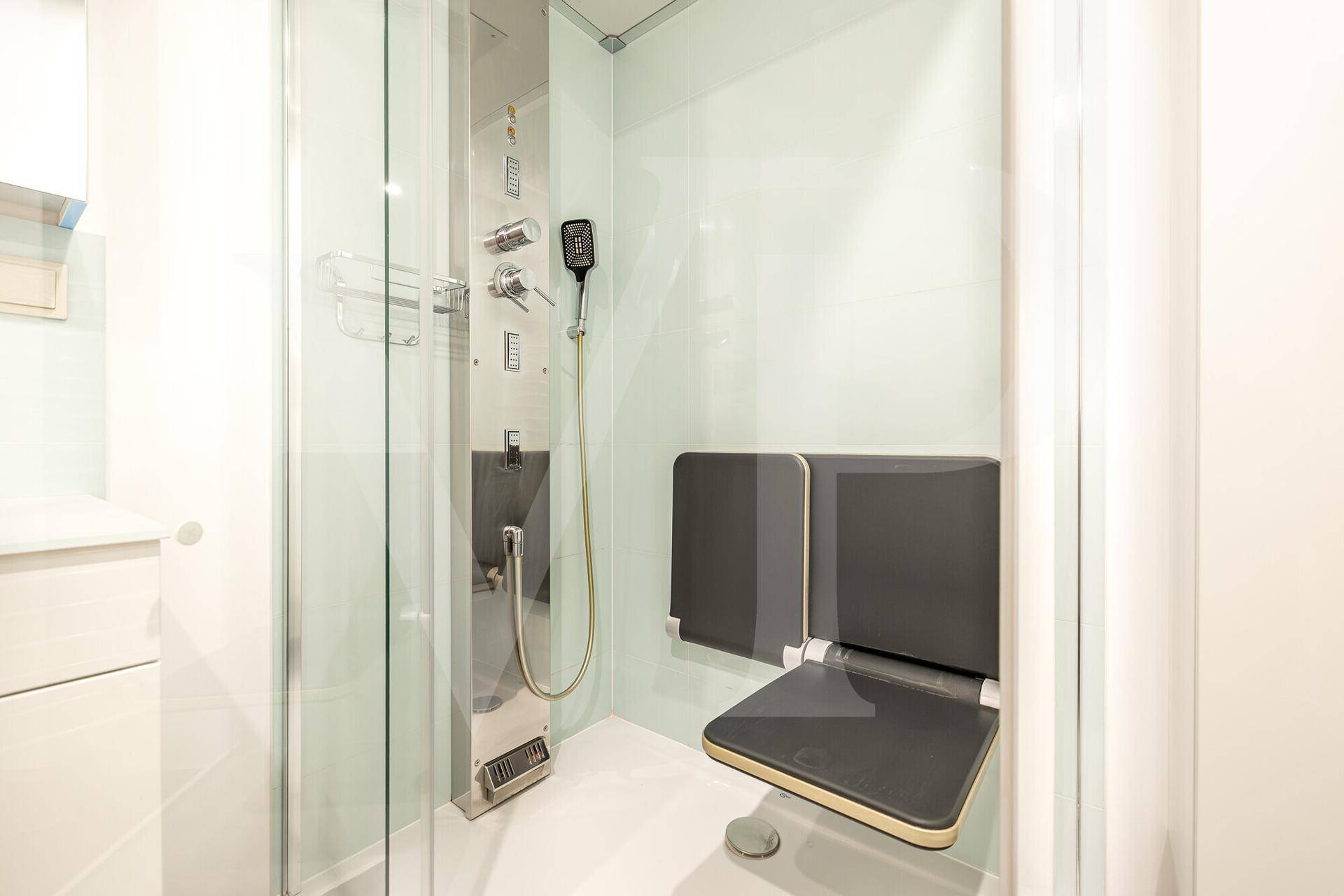Ebenerdige Dusche mit integriertem Sitz und modernen Armaturen, ideal für Komfort und Zugänglichkeit.