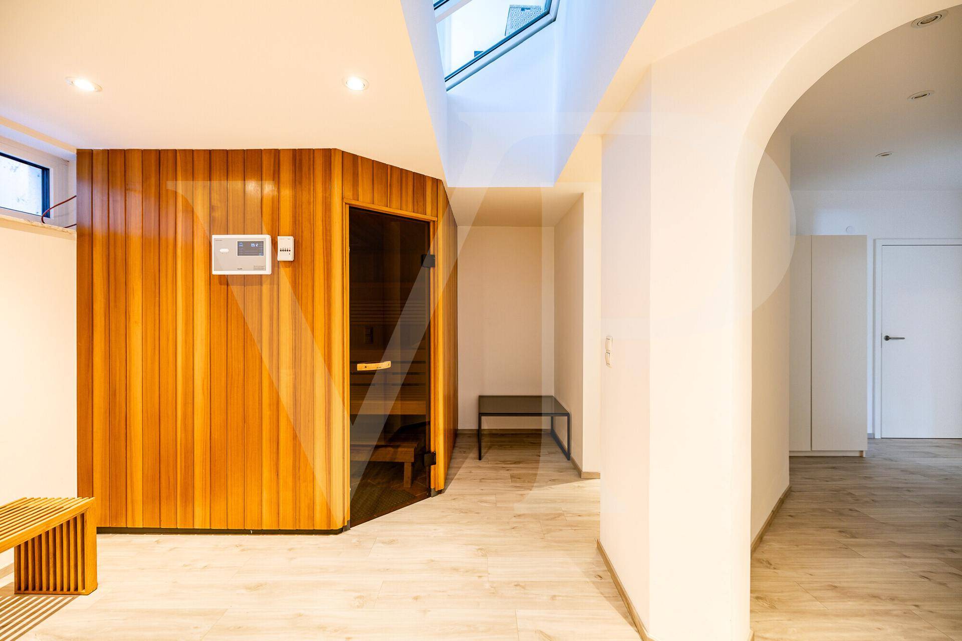 Heller Flur mit Holzboden und Zugang zu einer modernen Sauna mit Glasfront.