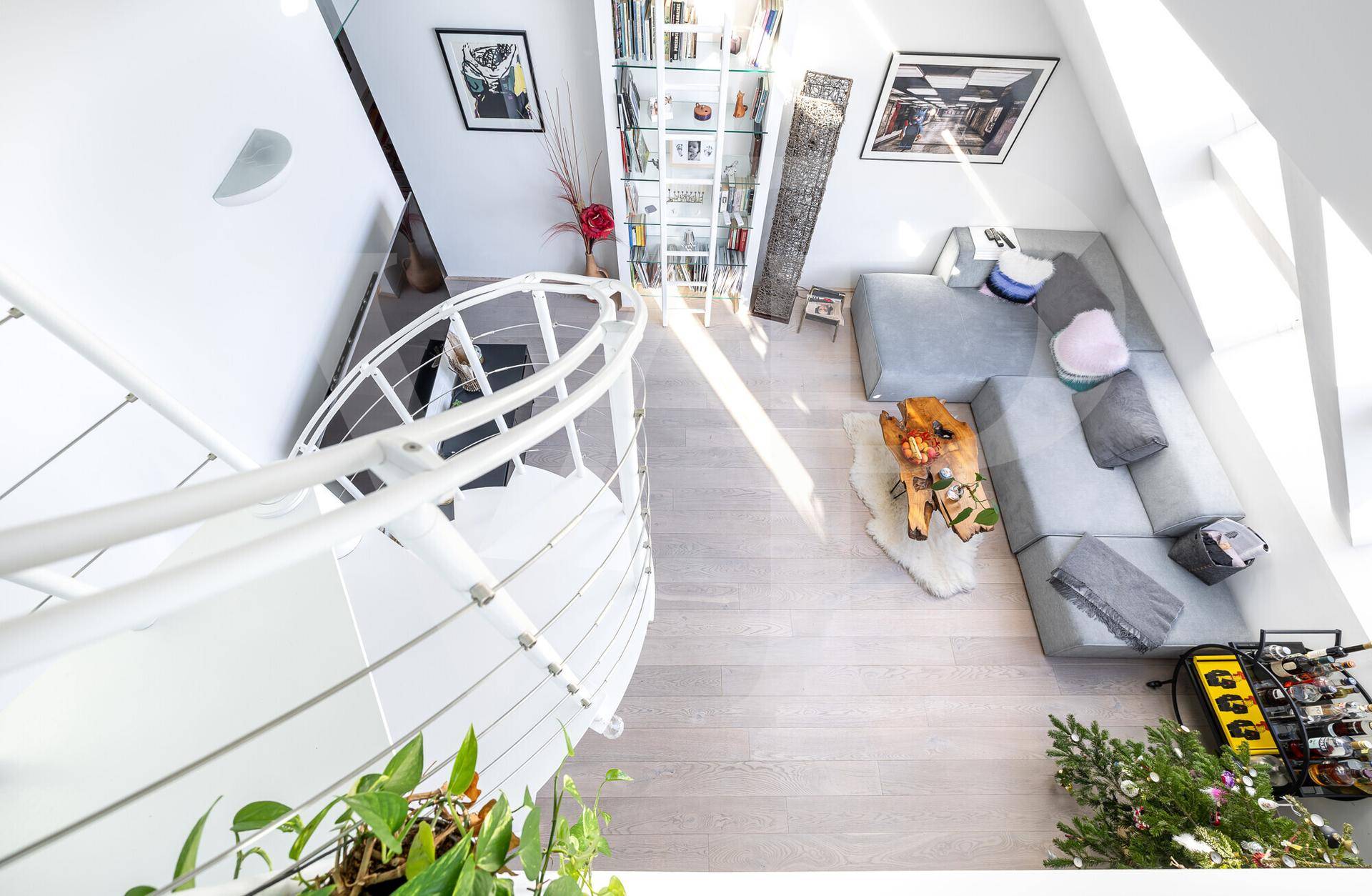 Blick von oben auf den hellen Wohnbereich mit Sofa und Wendeltreppe.