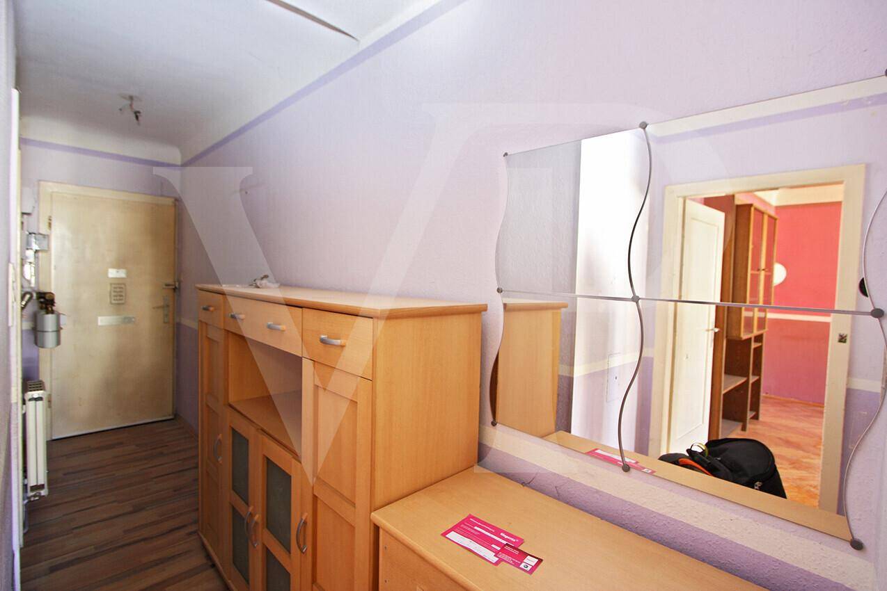 Heller Flur mit Holzboden, Spiegel und einem Schrank, der zu weiteren Räumen führt.