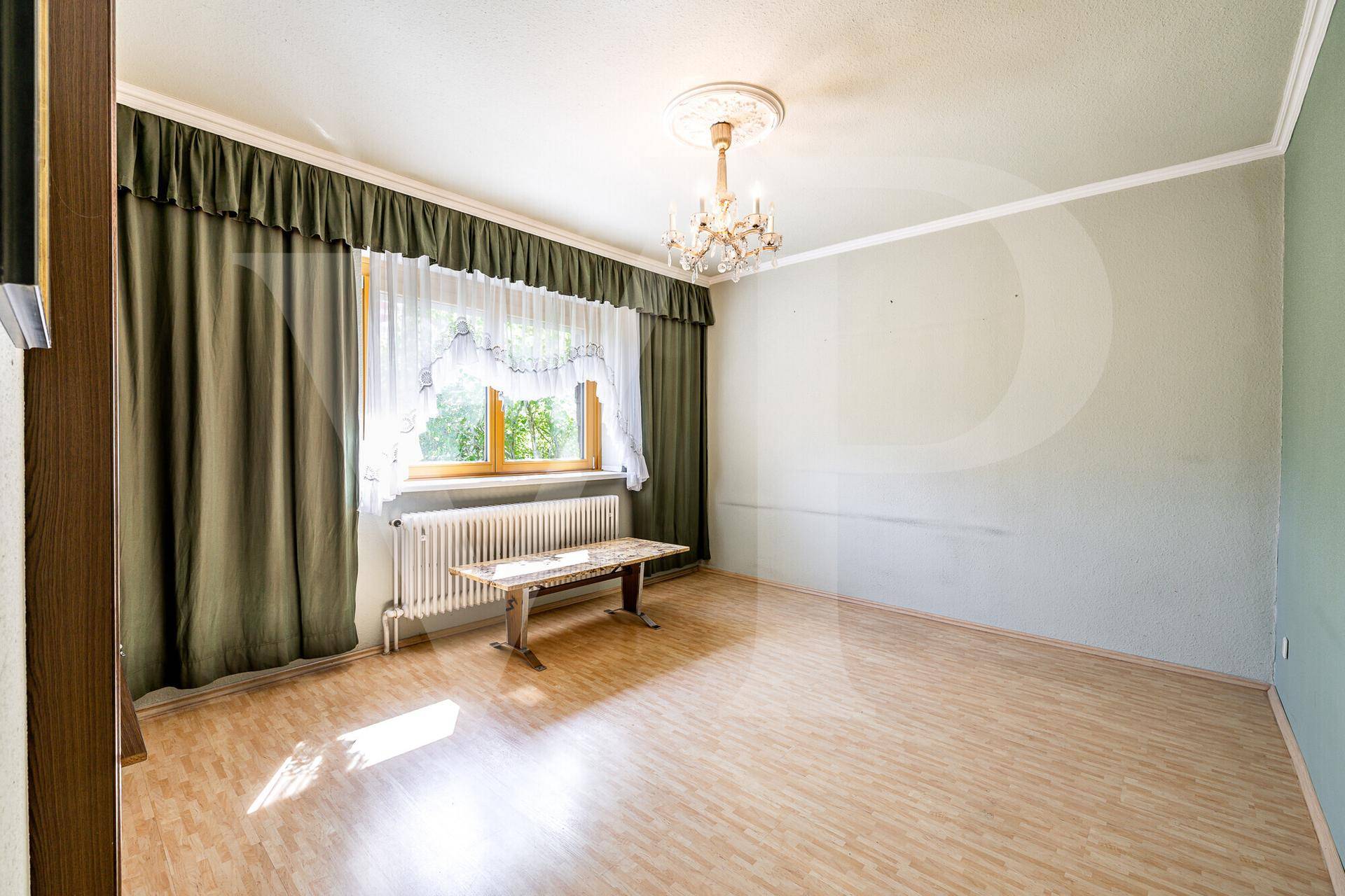 Helles Wohnzimmer mit Laminatboden, grünen Wänden und einem großen Fenster.