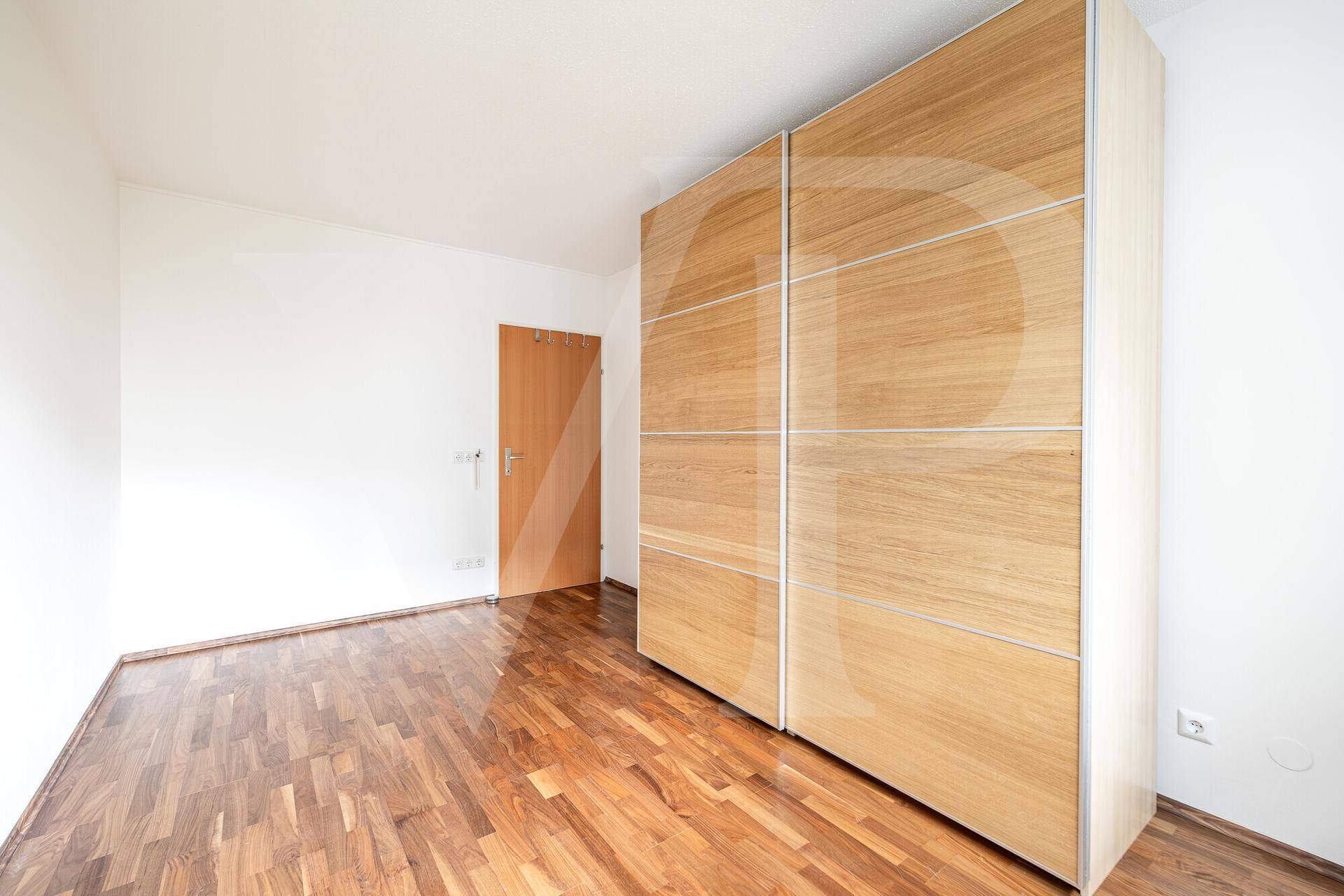 Geräumiges Schlafzimmer mit Holzboden und großem Kleiderschrank, bietet viel Stauraum.