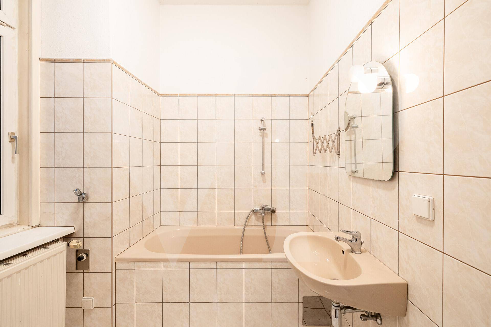 Badezimmer mit beigefarbenen Fliesen, Badewanne und Waschbecken.