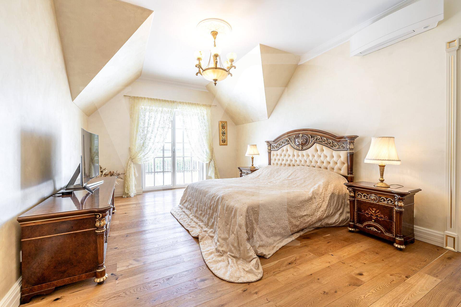 Geräumiges Schlafzimmer mit Holzboden, großem Bett, Kommoden und Zugang zum Balkon.