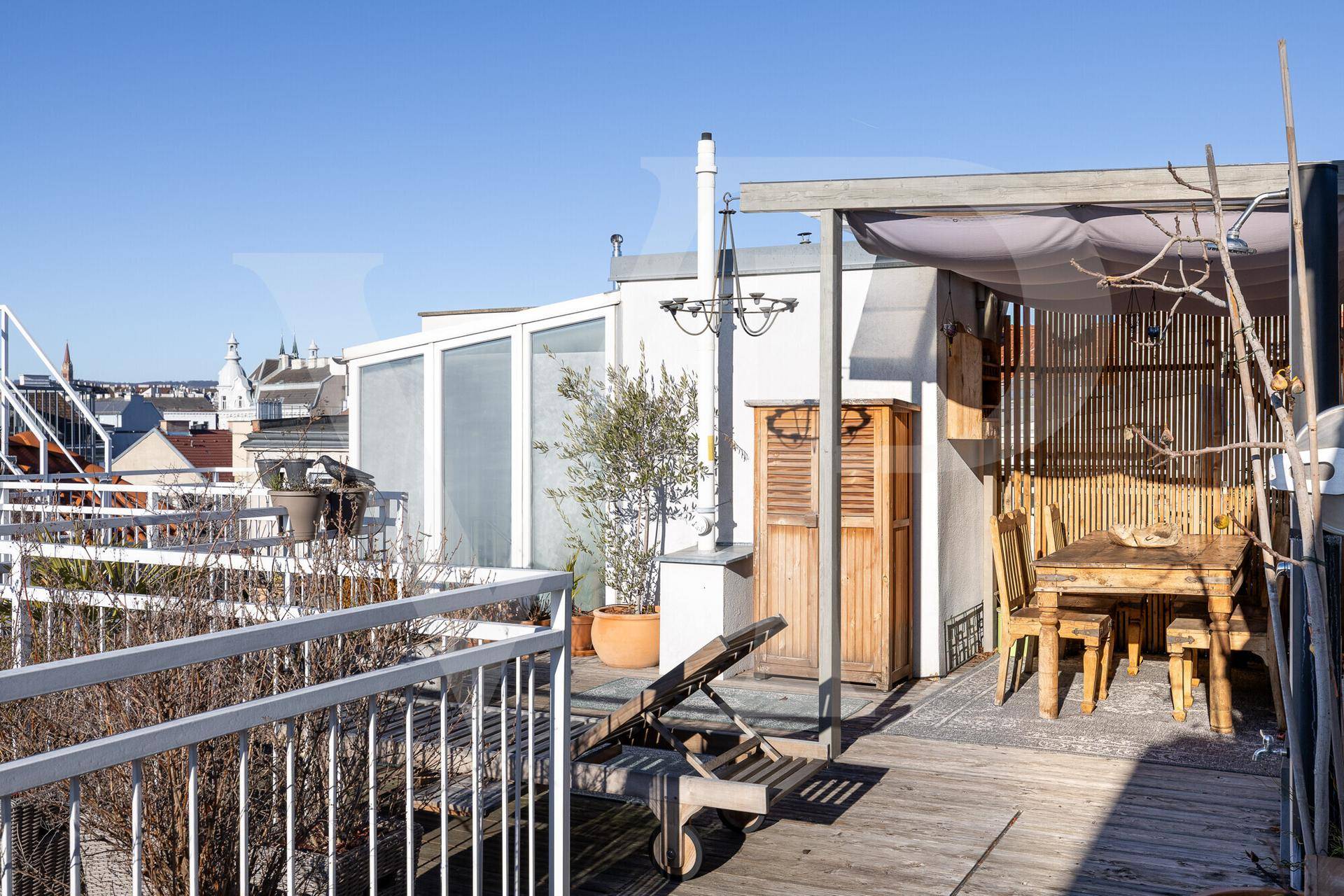 Gemütlicher Essbereich auf der Dachterrasse mit Holzmöbeln und Blick auf die umliegende Stadtlandschaft.