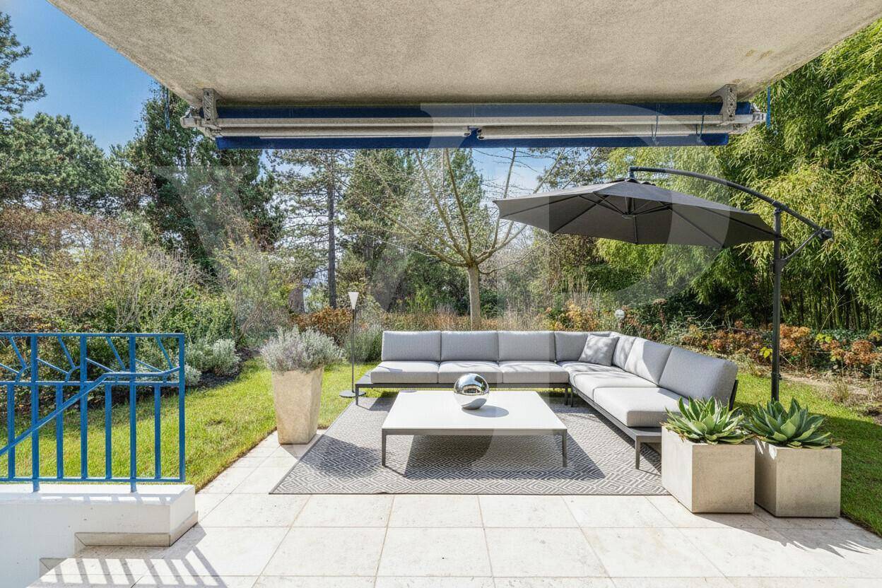 Geräumige Terrasse mit modernen Loungemöbeln und Sonnenschirm, ideal zum Entspannen im Grünen.