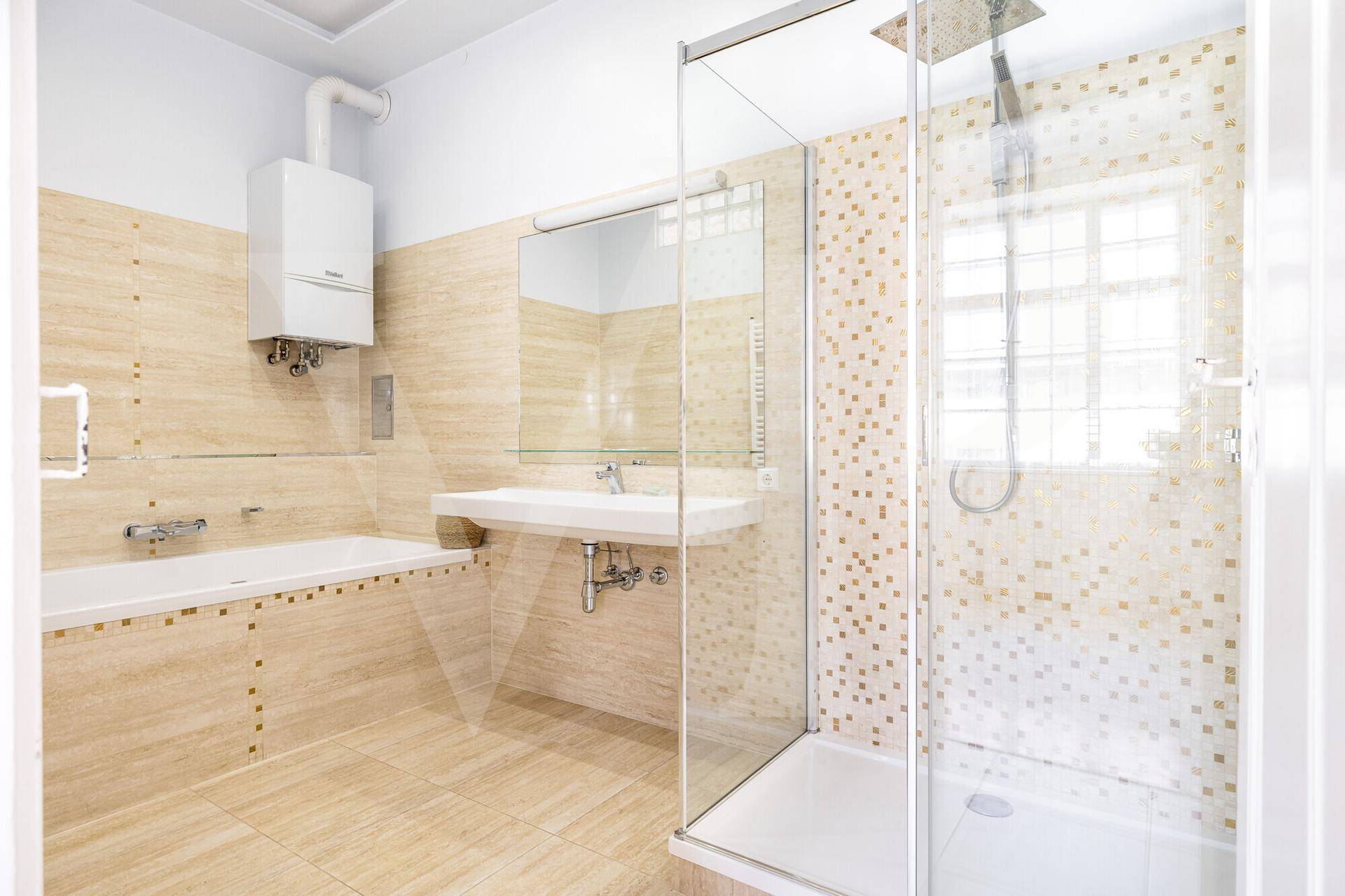 Modernes Badezimmer mit Duschkabine, Badewanne, Waschbecken und beigefarbenen Fliesen.