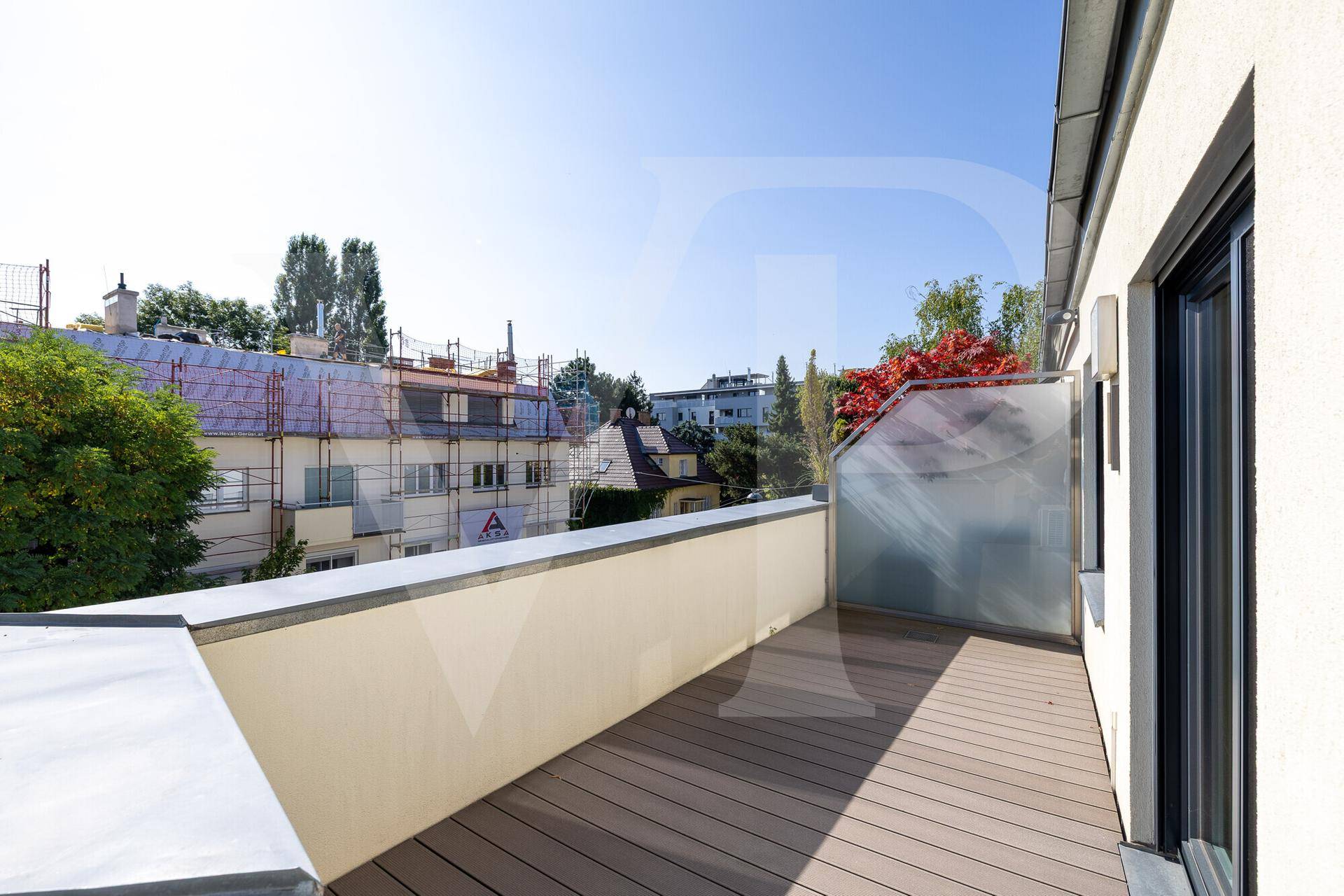 Geräumige Terrasse mit Blick auf die Nachbarschaft und umliegende Gebäude unter blauem Himmel.