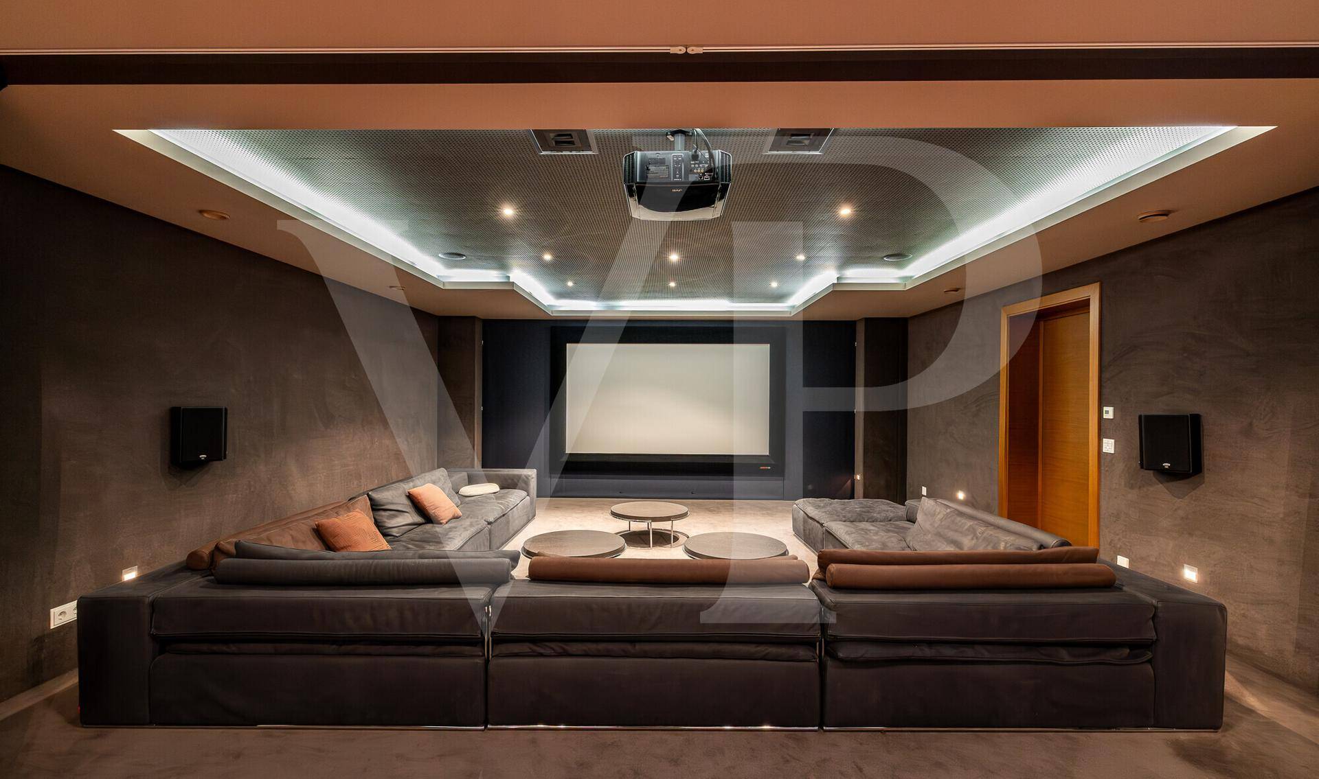 Exklusiver Medienraum mit großer Leinwand, bequemen Sofas und indirekter Beleuchtung.