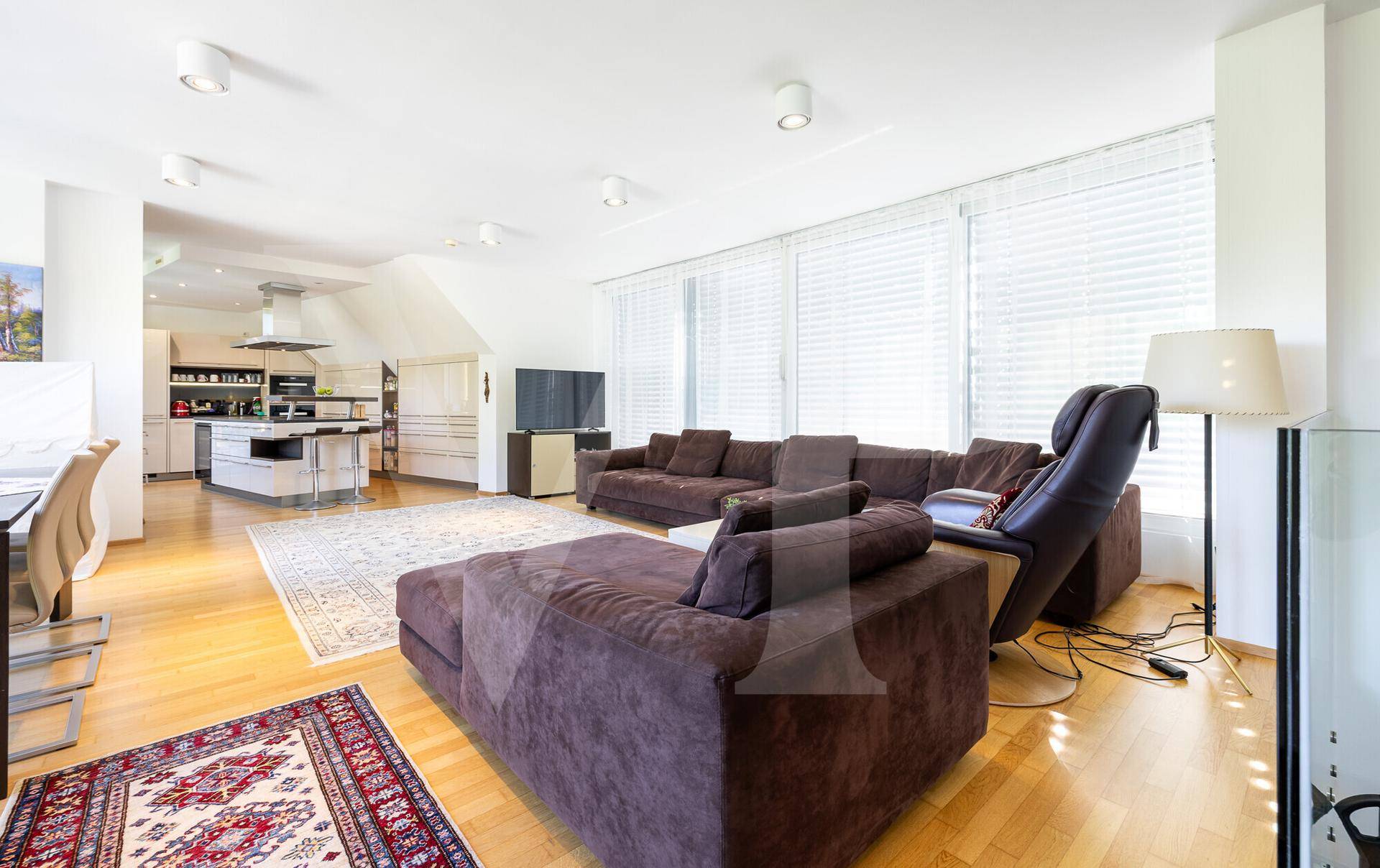 Heller Wohnbereich mit bequemen Sofas, Holzboden und Blick auf die Küche im Hintergrund.