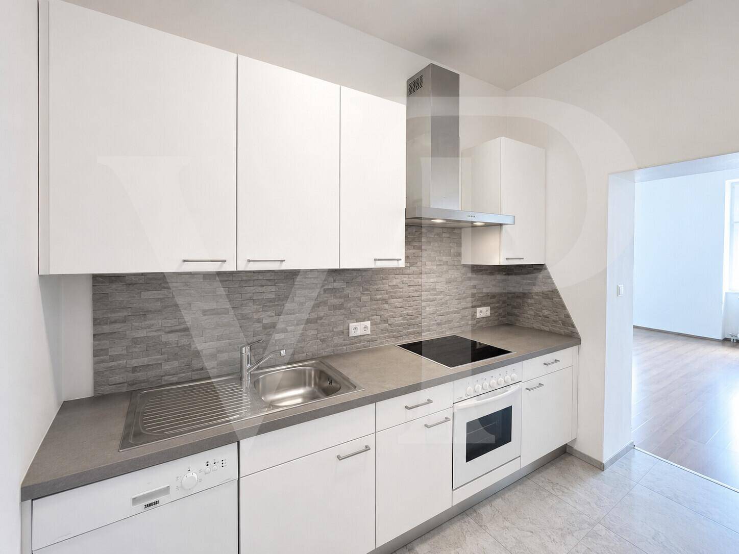 Helle, moderne Küche mit weißen Hochglanzfronten, grauer Arbeitsplatte, stilvoller Fliesenrückwand und integrierten Küchengeräten.