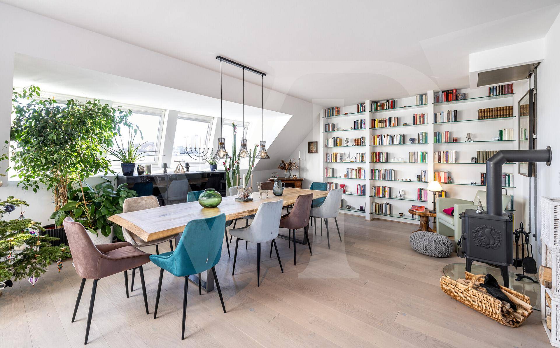 Geräumiger Essbereich mit Holztisch, bunten Stühlen und einem eleganten Holzofen.
