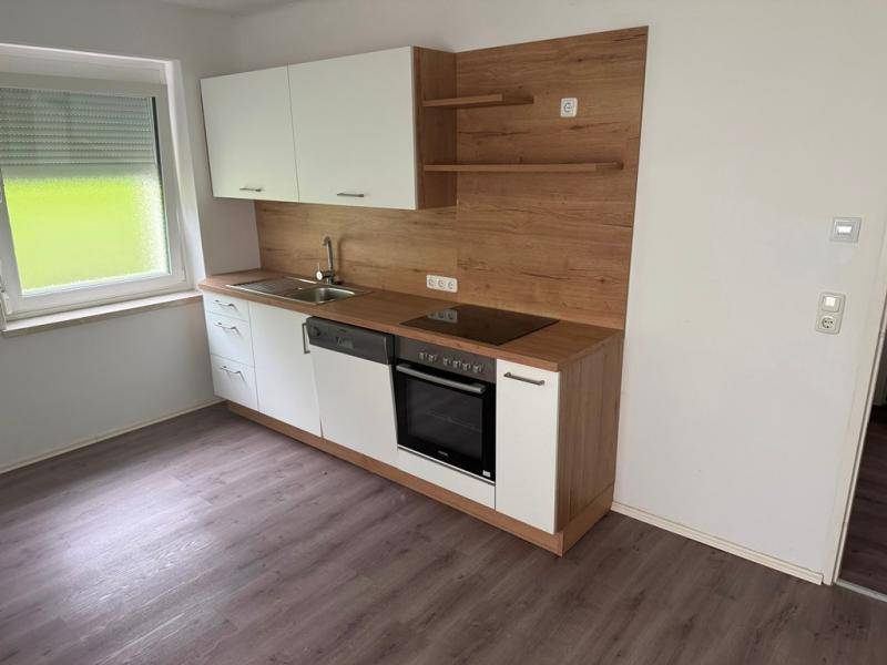Moderne Einbauküche mit weißen Schränken, Holzakzenten und integrierten Geräten.