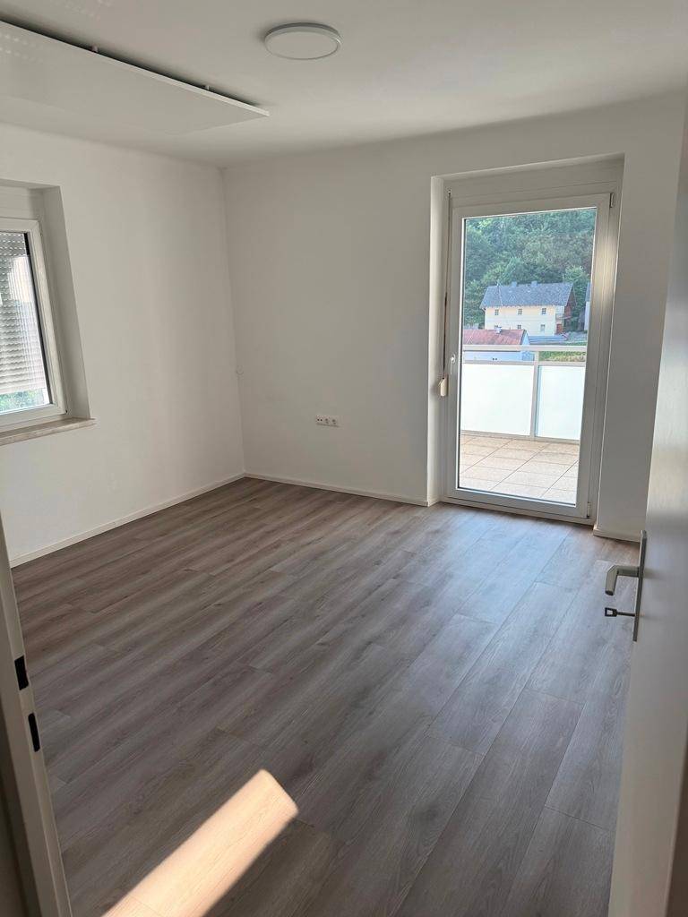 Helles Zimmer mit Laminatboden und Zugang zu einer Terrasse oder einem Balkon.